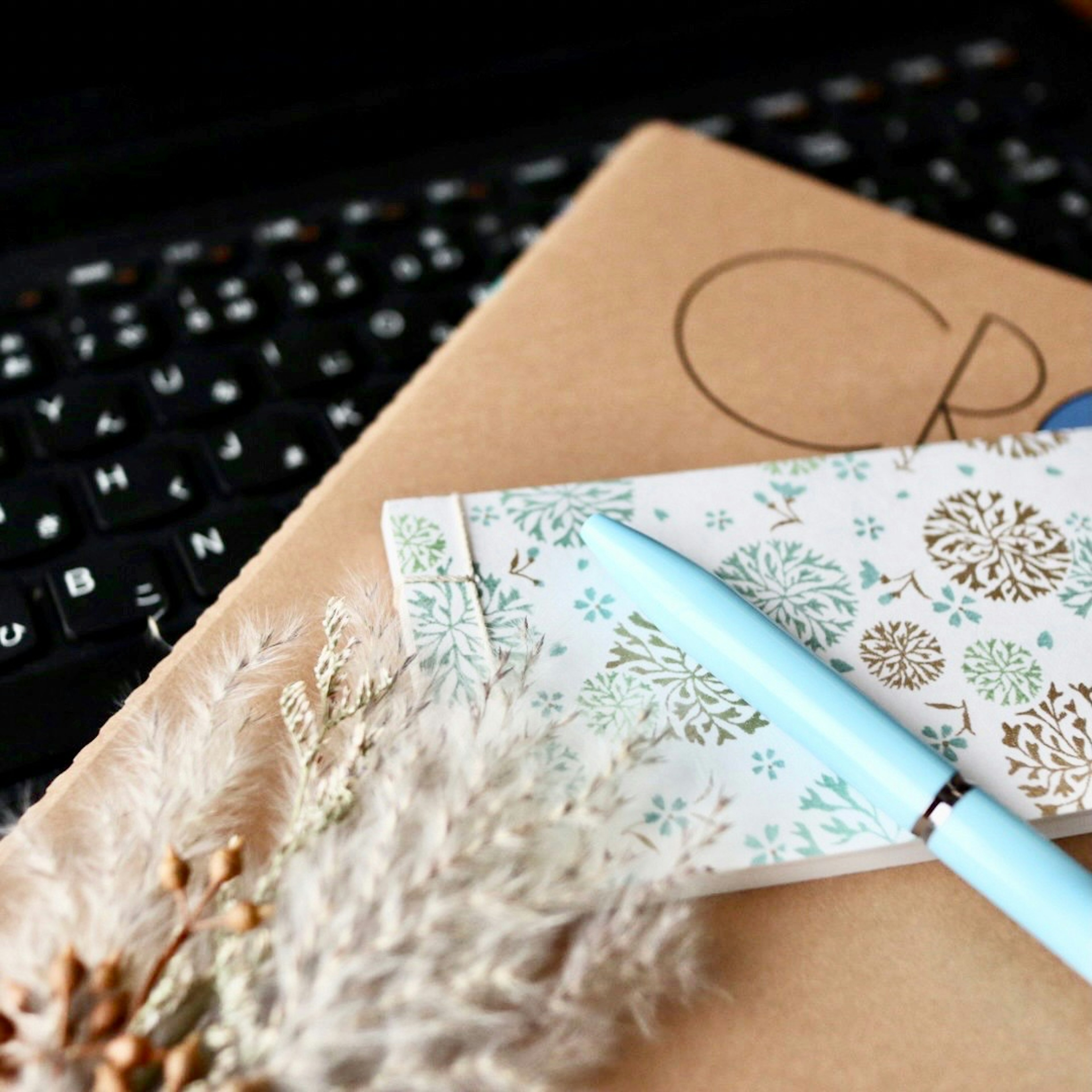 A blue pen and decorative card on a desk with plant decor