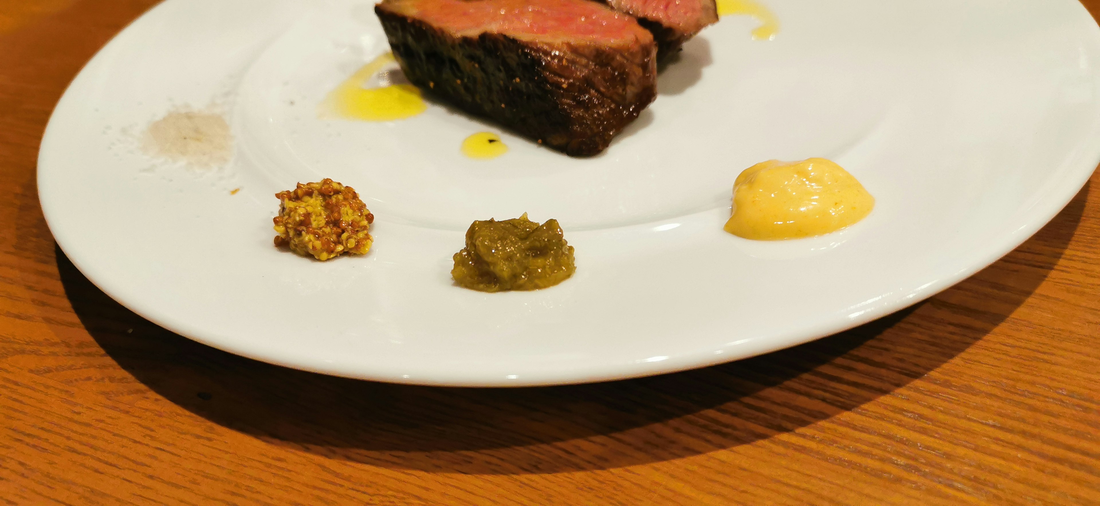 Assiette avec un morceau de viande et trois types de sauces