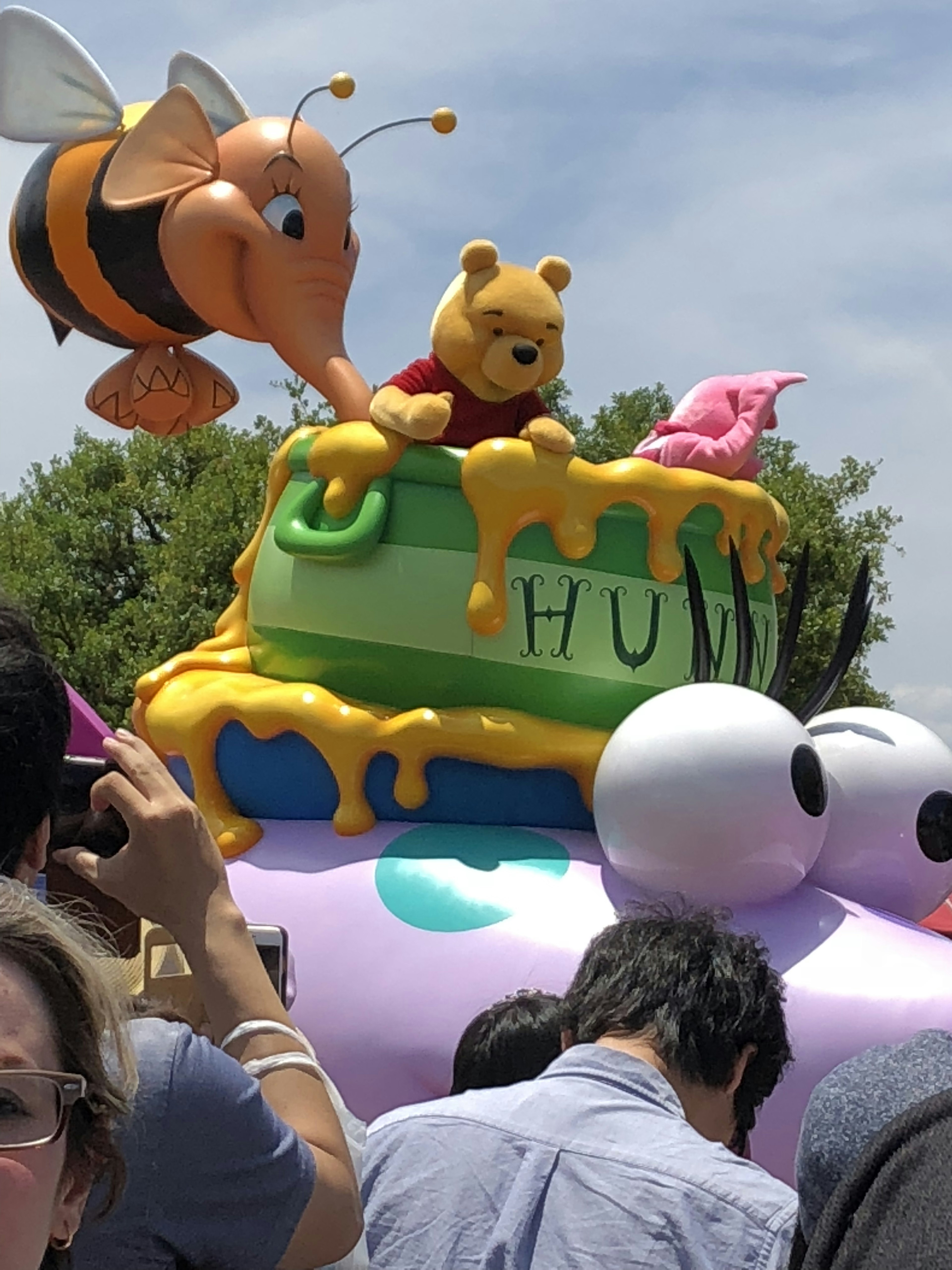 Float parade berwarna dengan Winnie the Pooh dan seekor lebah di atas kue madu