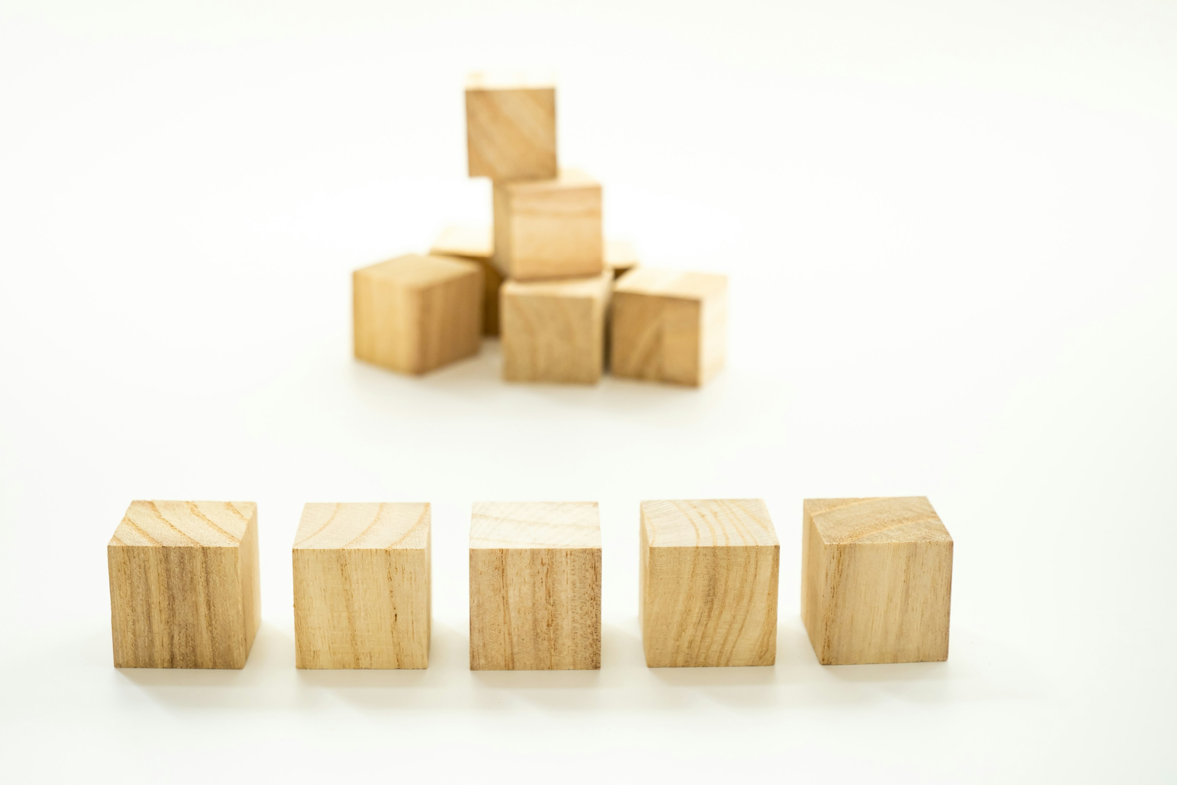 Cubes de madera dispuestos sobre un fondo blanco con algunos apilados en la parte posterior