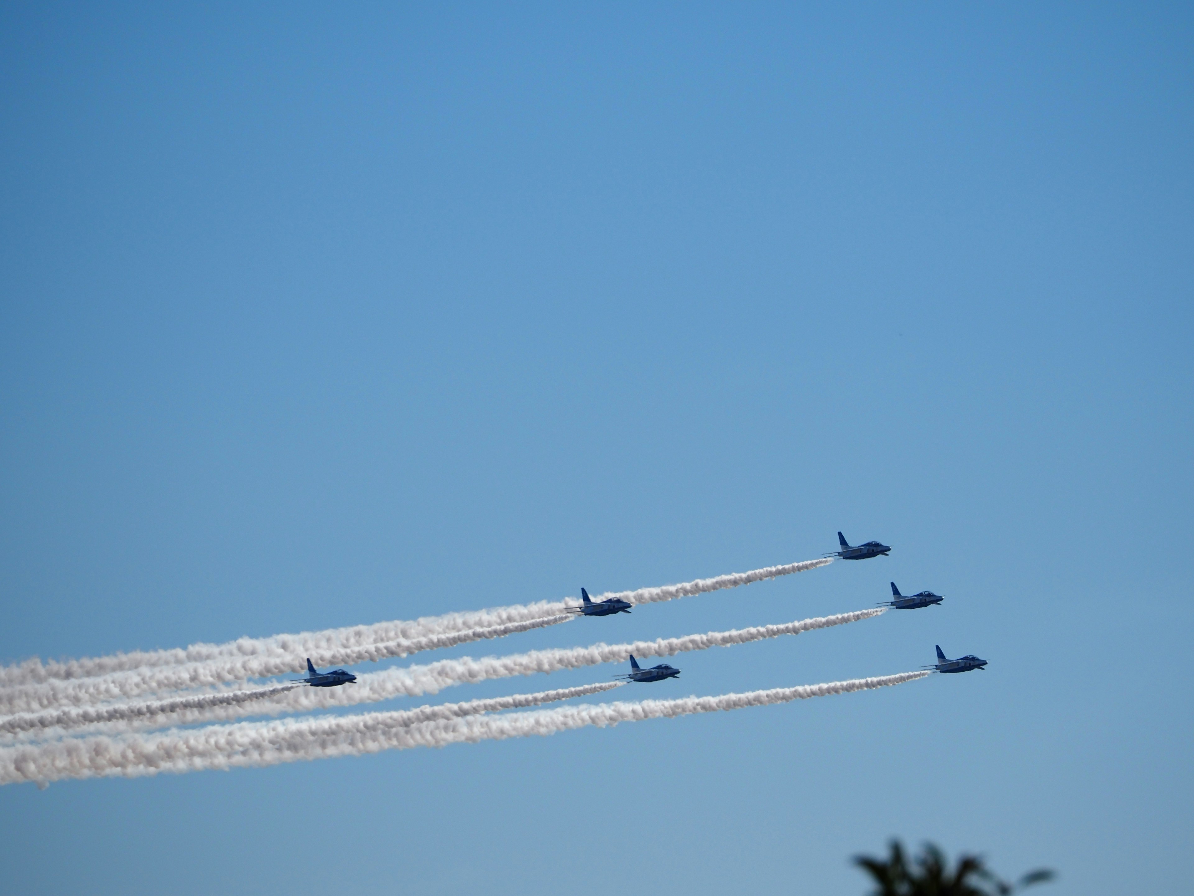 Formation von Flugzeugen, die gegen einen blauen Himmel fliegen und weiße Spuren hinterlassen