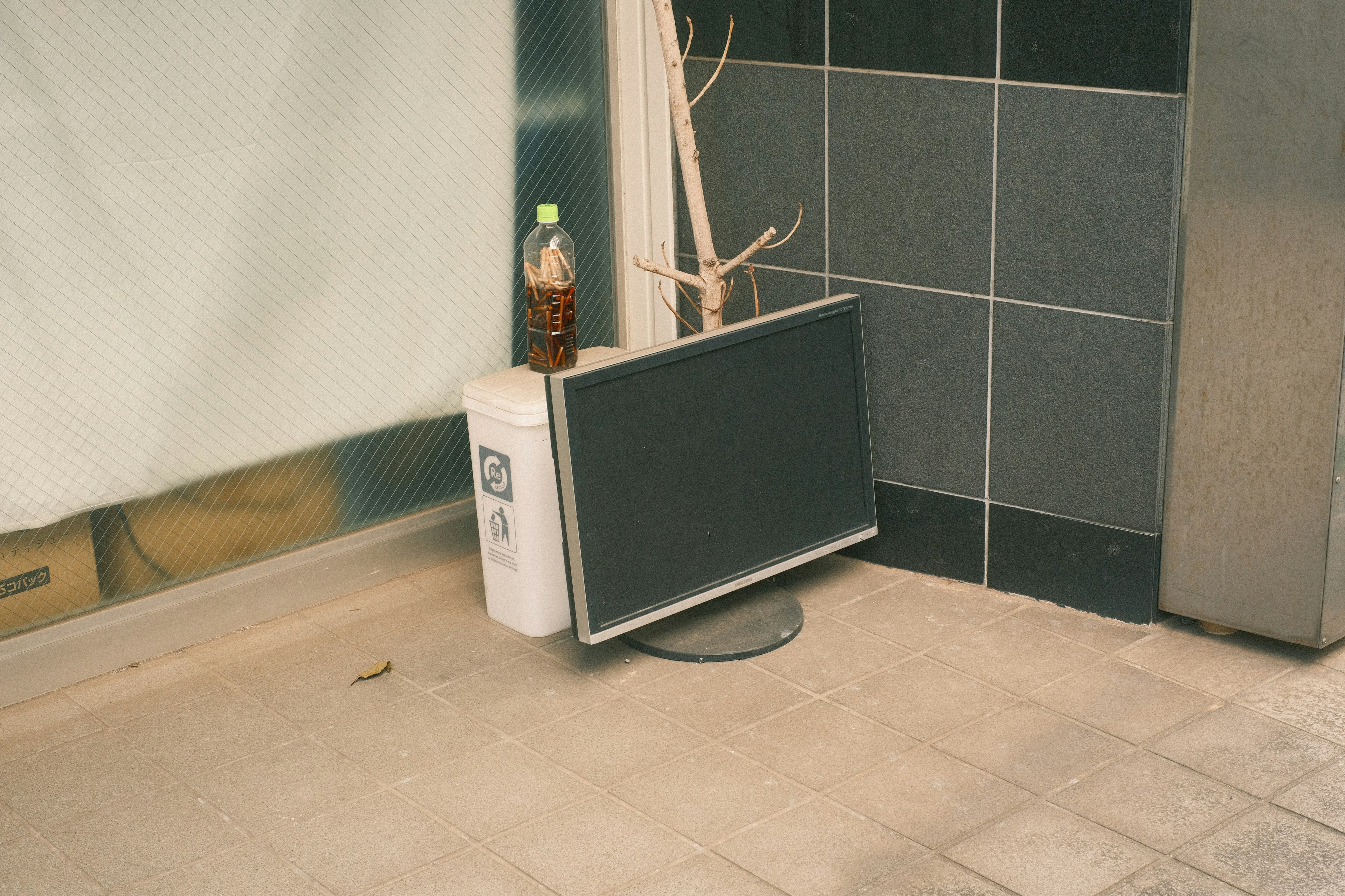 Abandoned monitor leaning against a trash can in a street corner