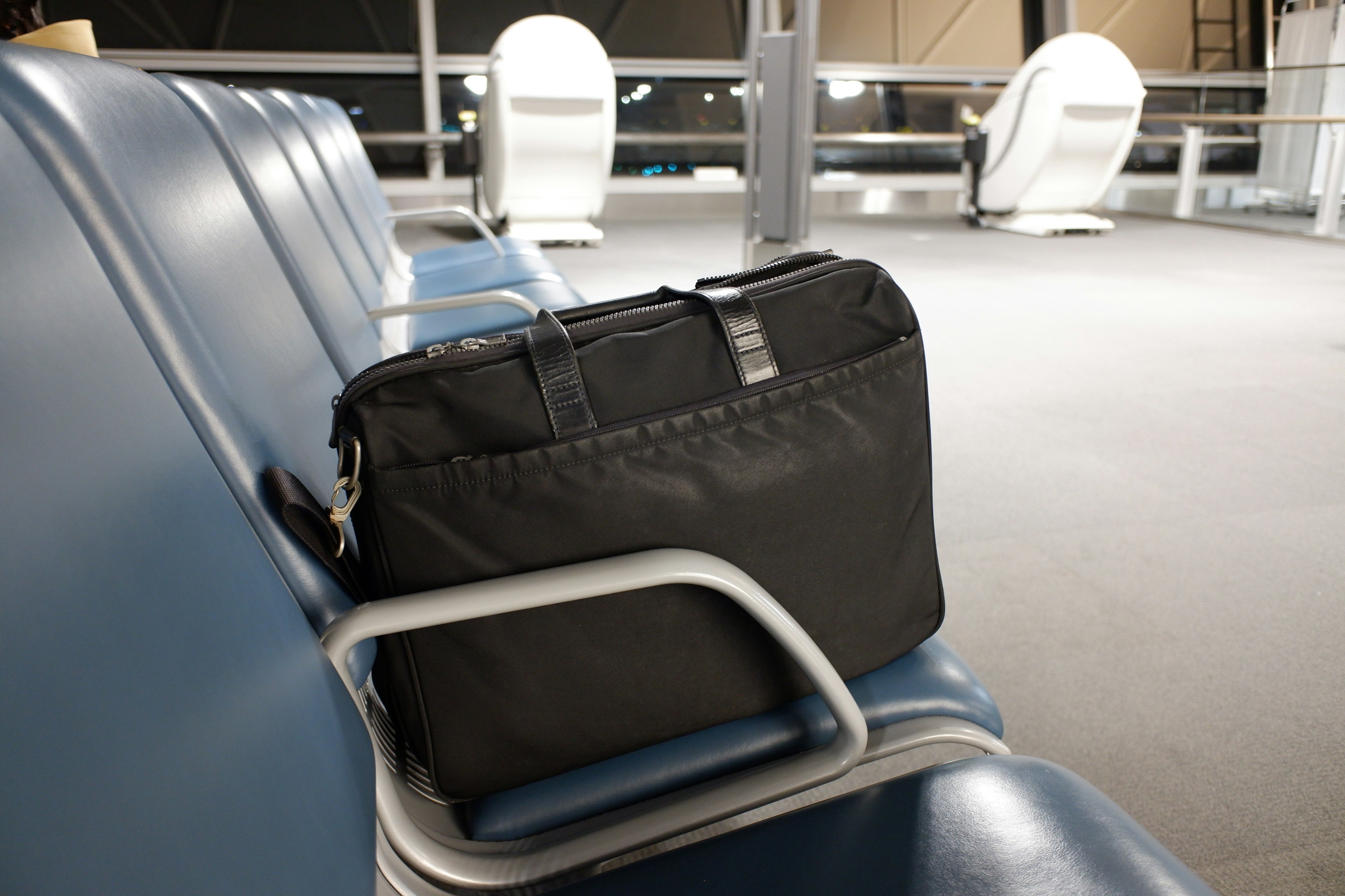 Black business bag resting on a seat in an airport waiting area