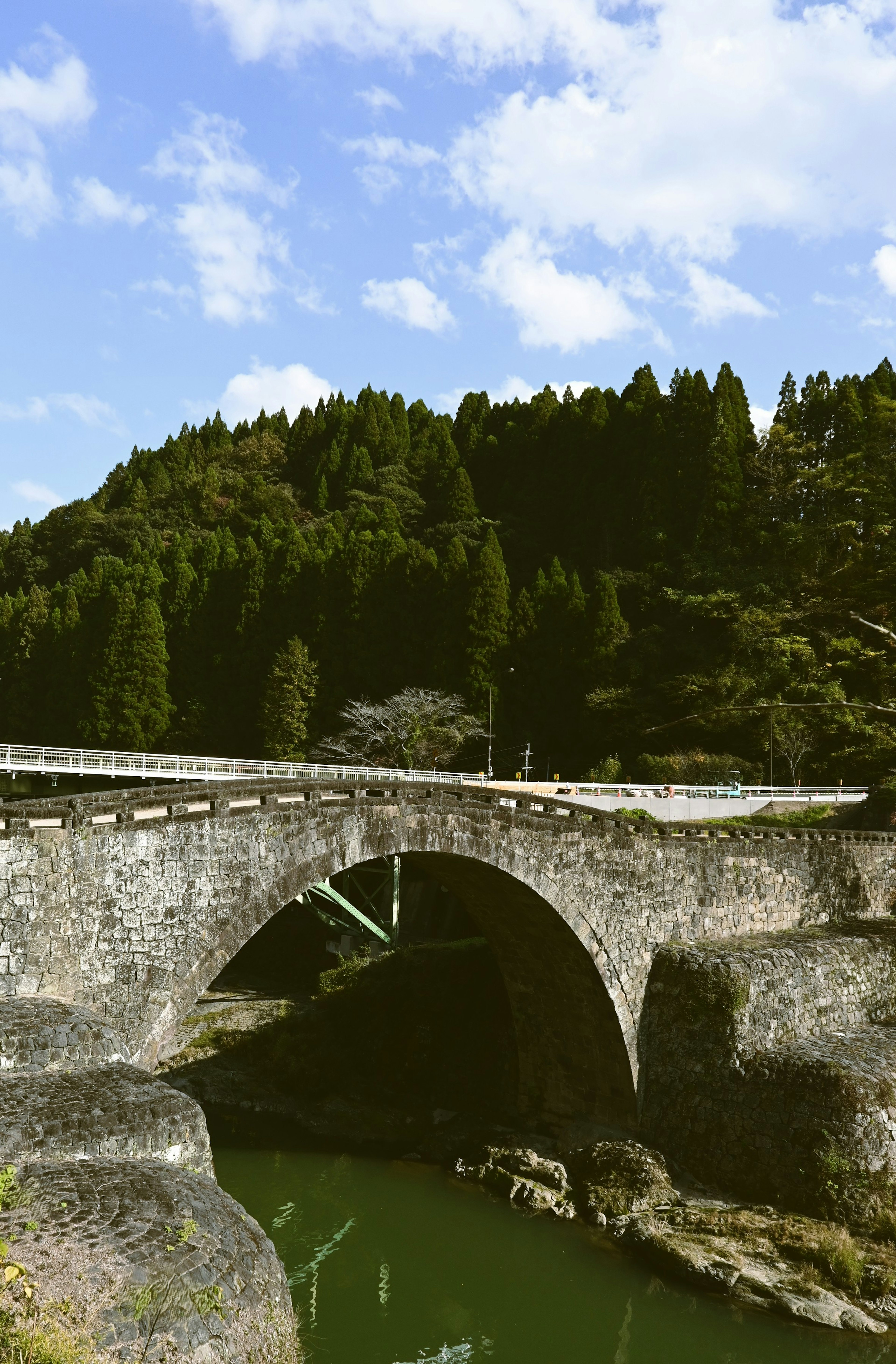 Alter Steinbogenbrücke umgeben von üppigem Grün und blauem Himmel