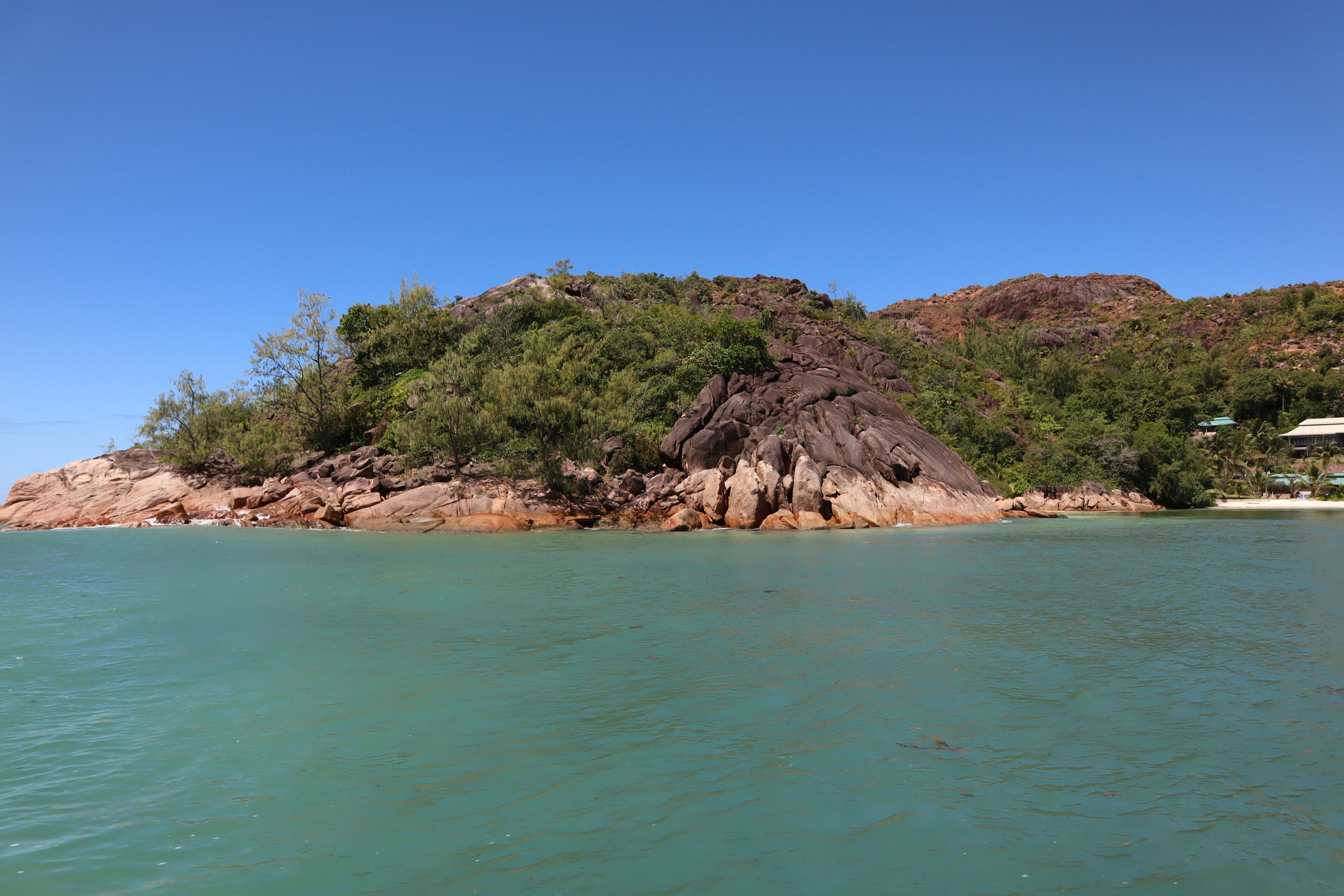 Scenic view of a green hill by the blue sea