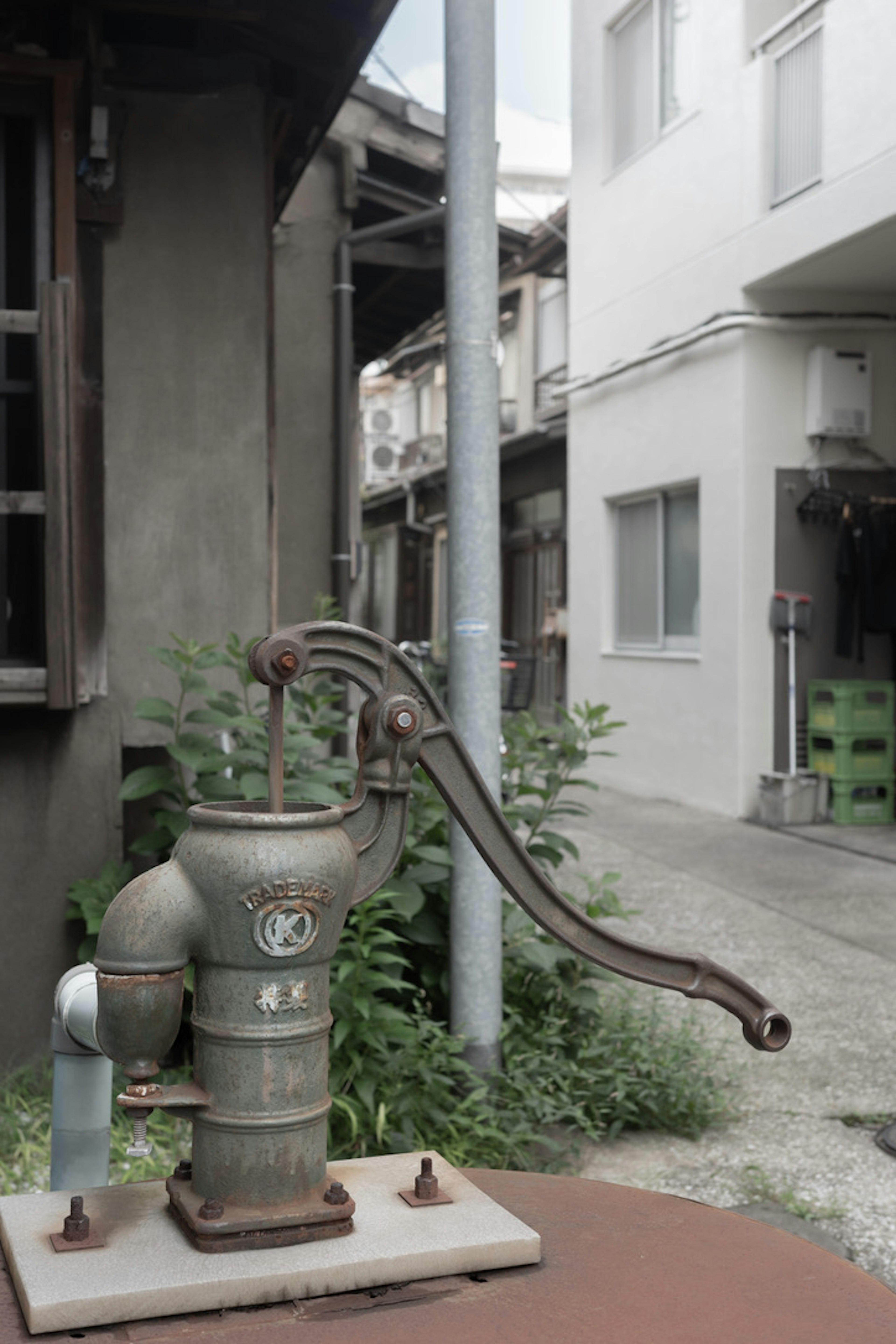 An old water pump located on a street with buildings in the background