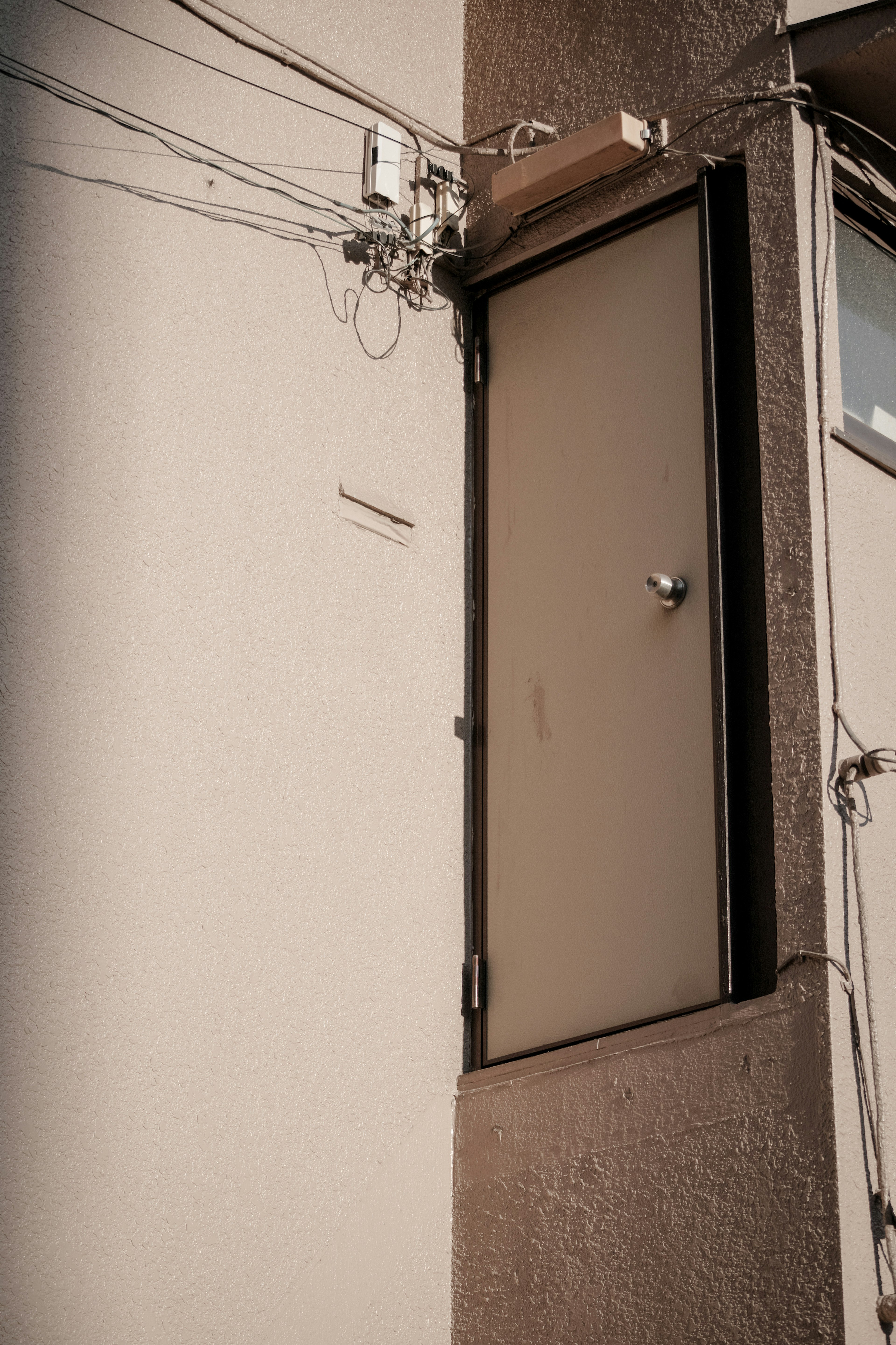 Small door located high on a wall with visible wires