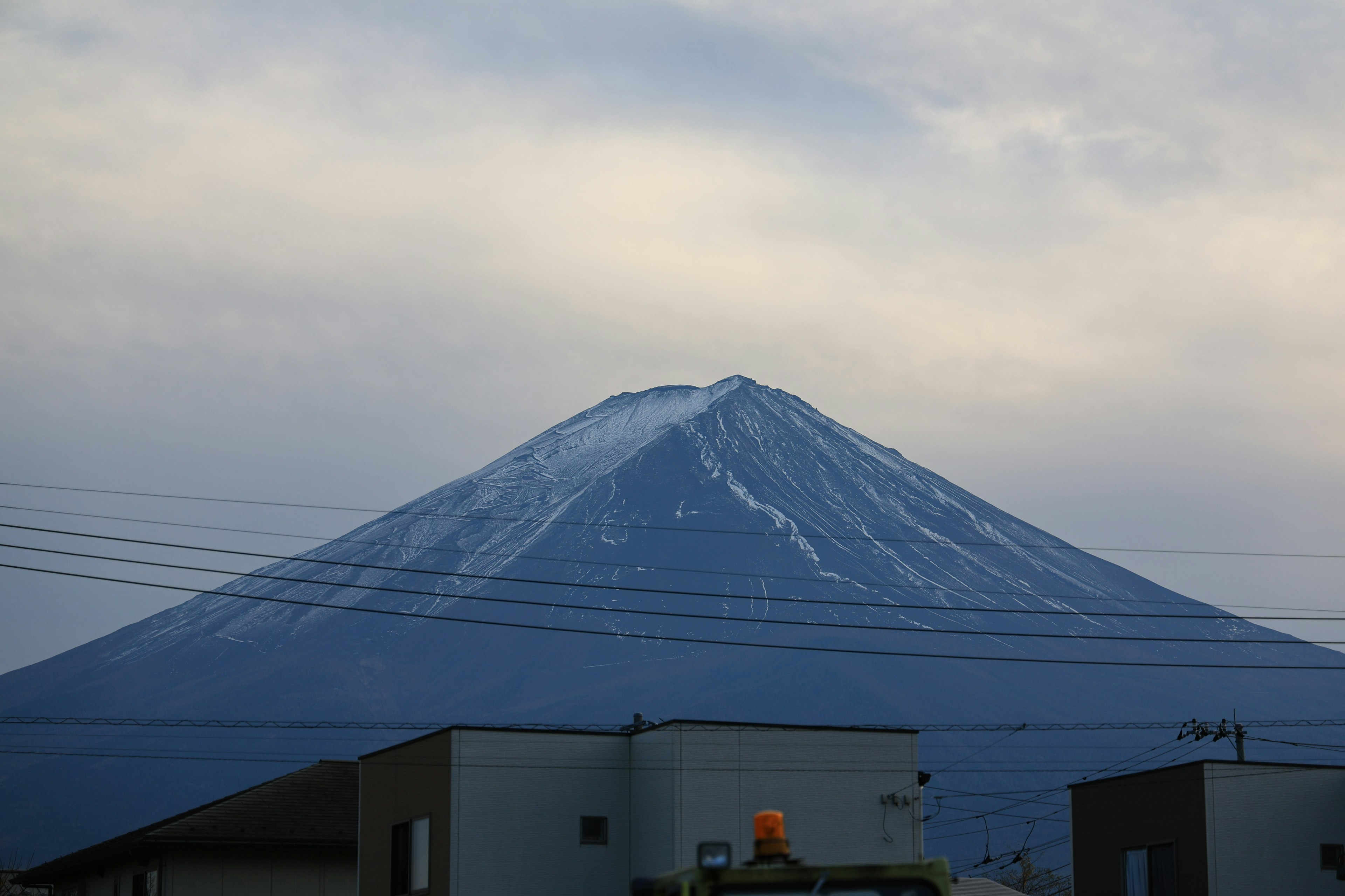 ทิวทัศน์ที่สวยงามของภูเขาฟูจิที่มีหิมะปกคลุมและเงาของบ้าน