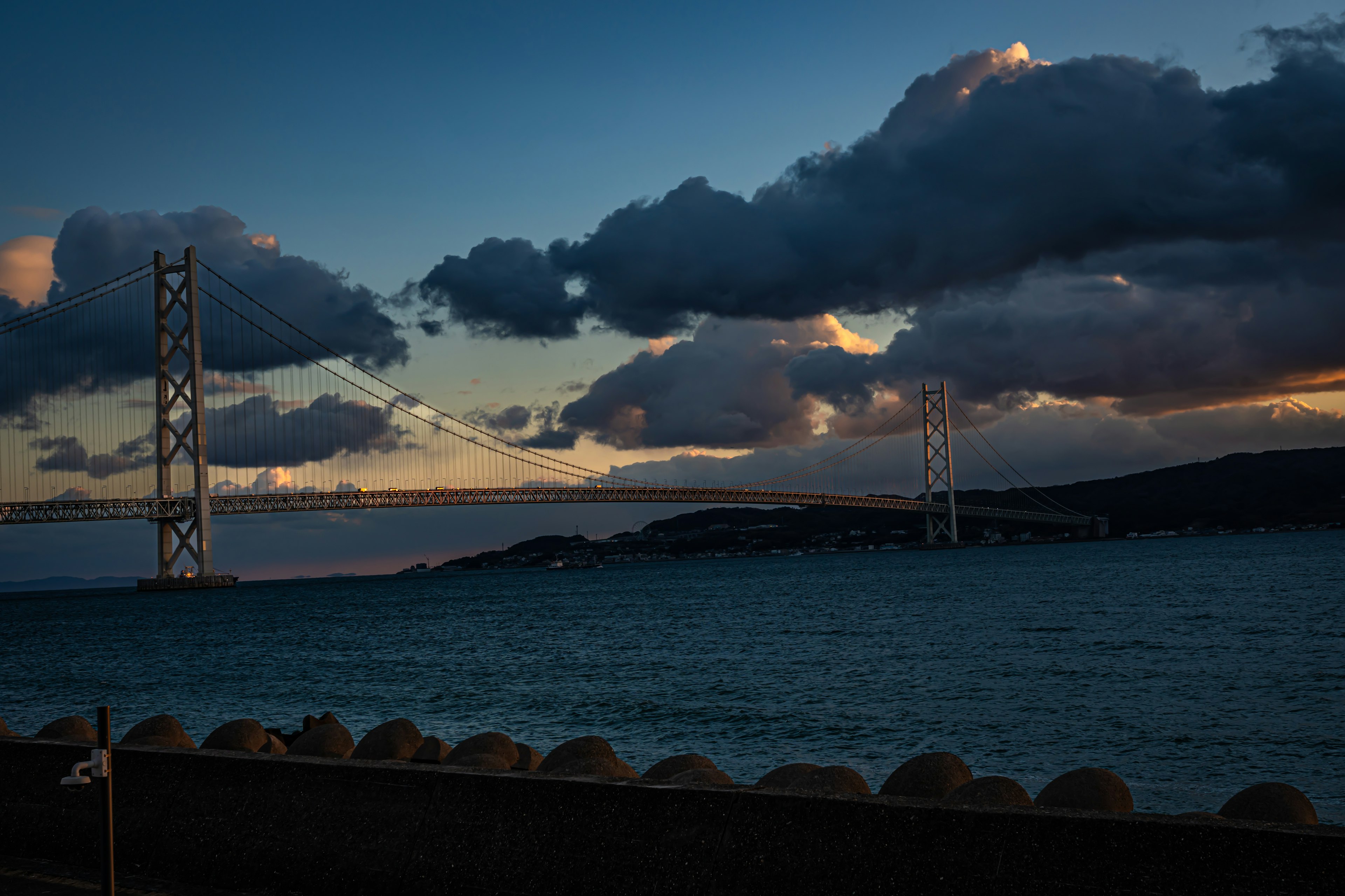 Dusk scene of the sea with bridges dark clouds and blue water