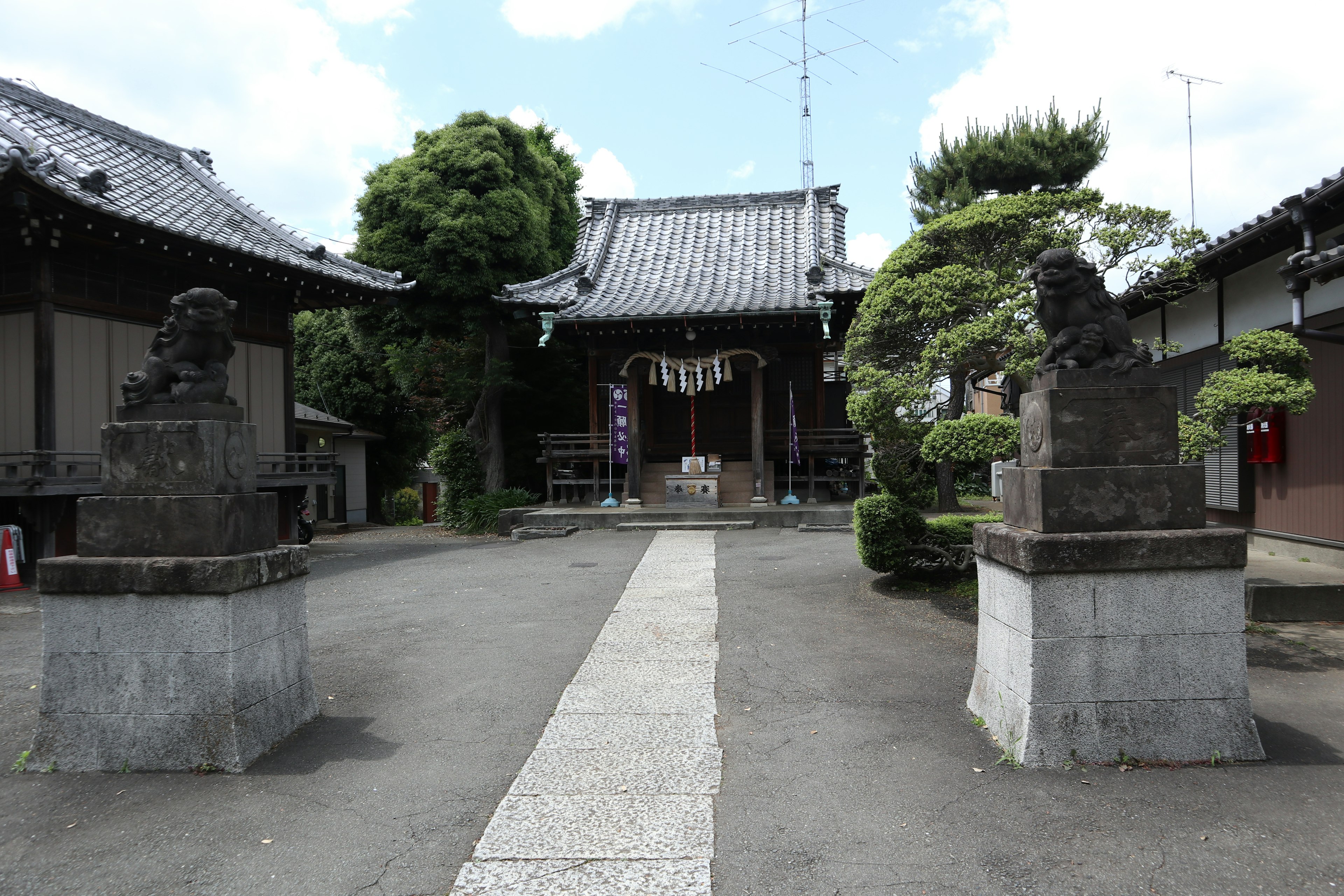 寺院の入り口にある狛犬の像と庭の木々がある風景