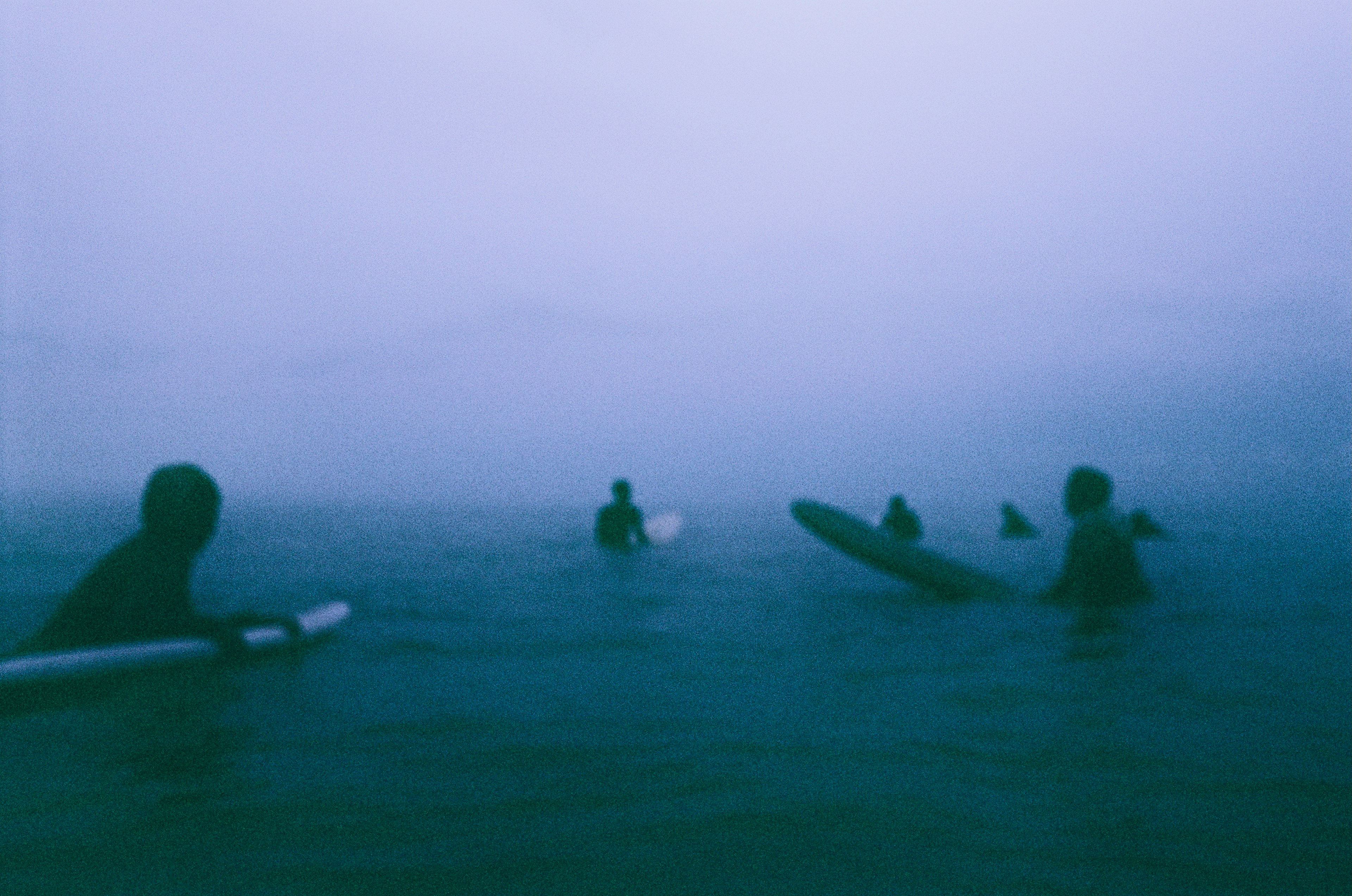 Silhouettes de surfeurs dans un océan brumeux