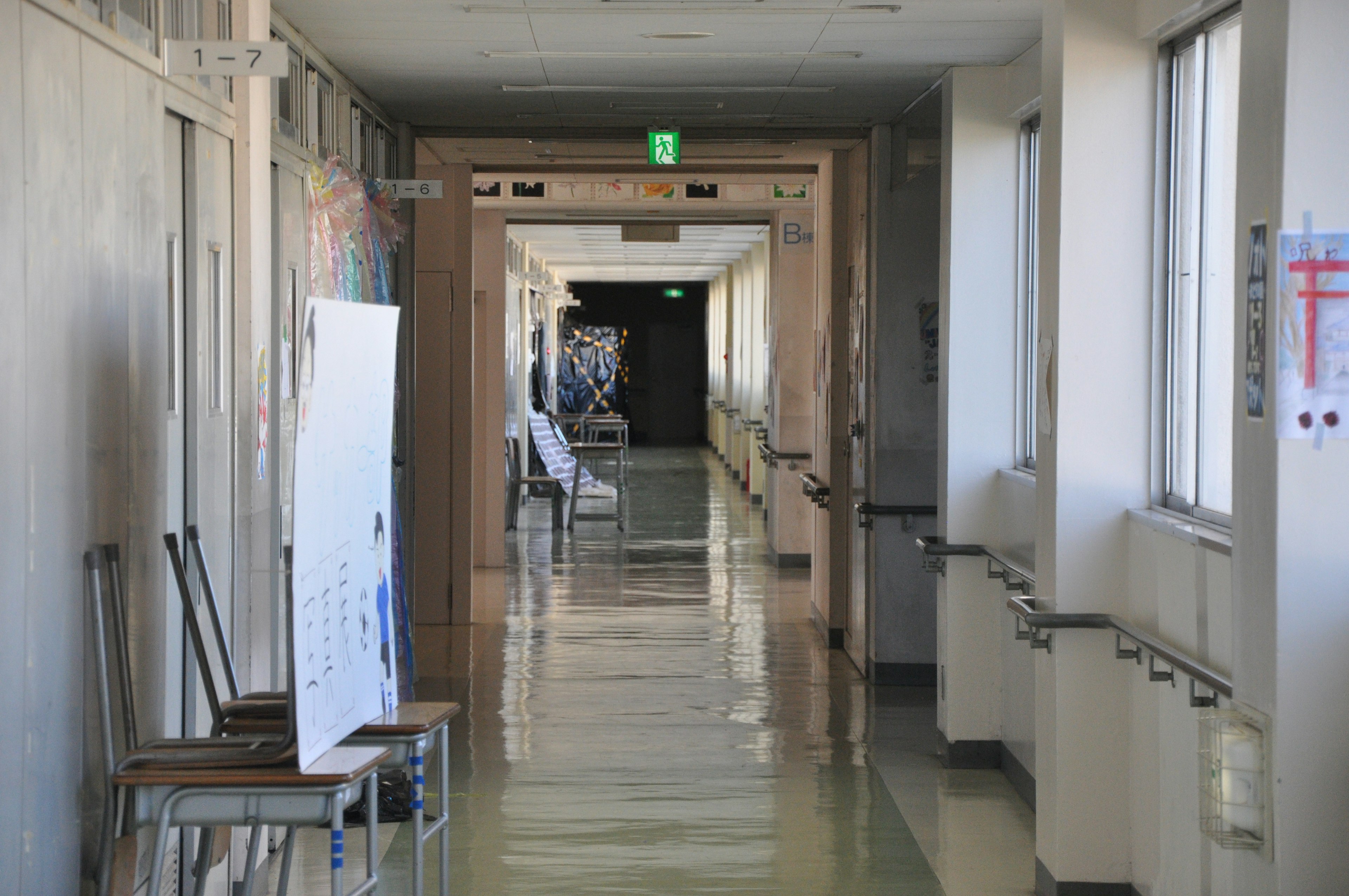 Ein langer Krankenhausflur mit schwachem Licht Stühle und ein Schild entlang der Wände