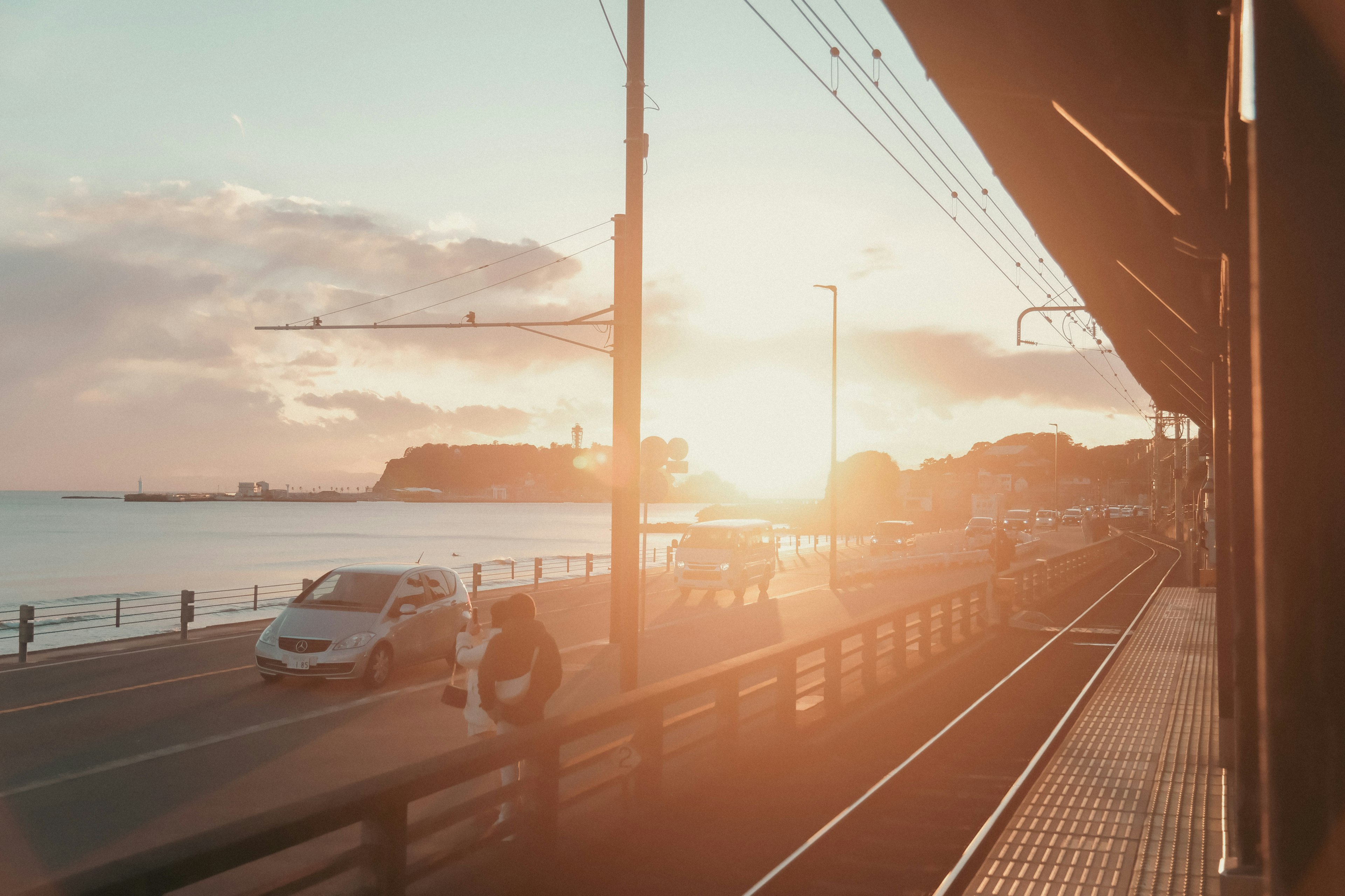 Malersicher Blick auf den Sonnenuntergang über dem Meer mit Autos und Fußgängern