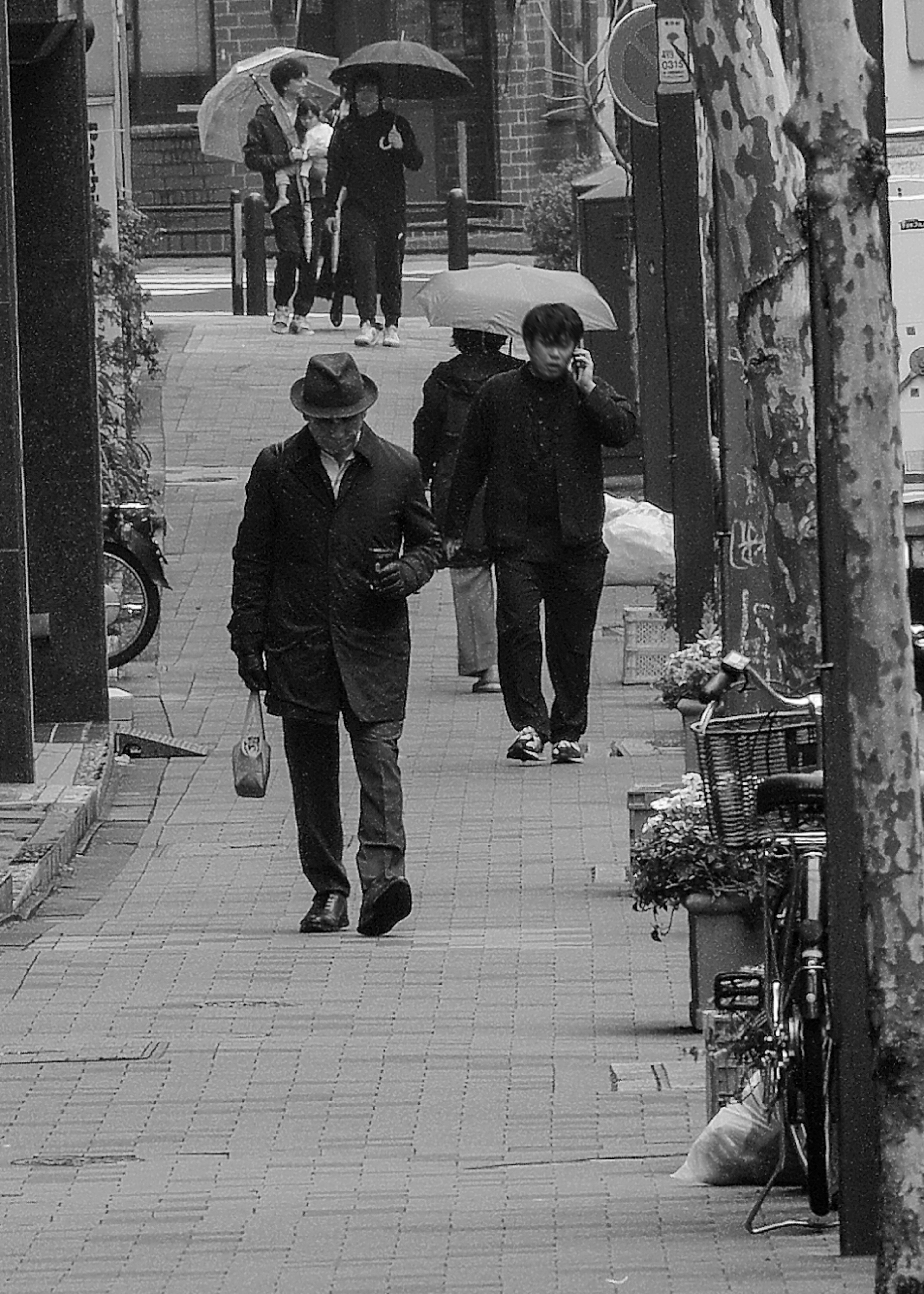 Personas caminando en una calle de la ciudad en blanco y negro con paraguas