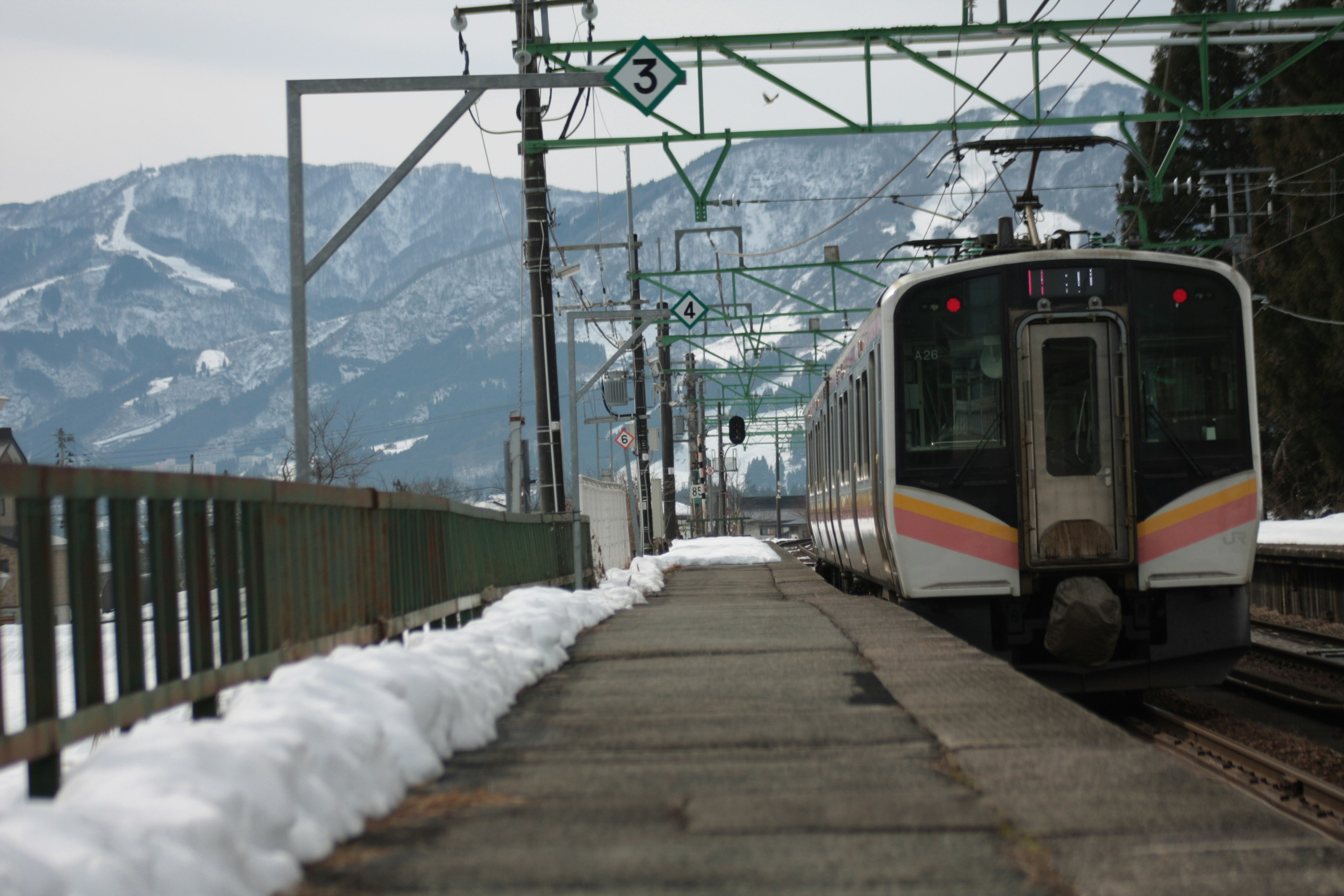 รถไฟที่สถานีมีหิมะและภูเขาอยู่เบื้องหลัง