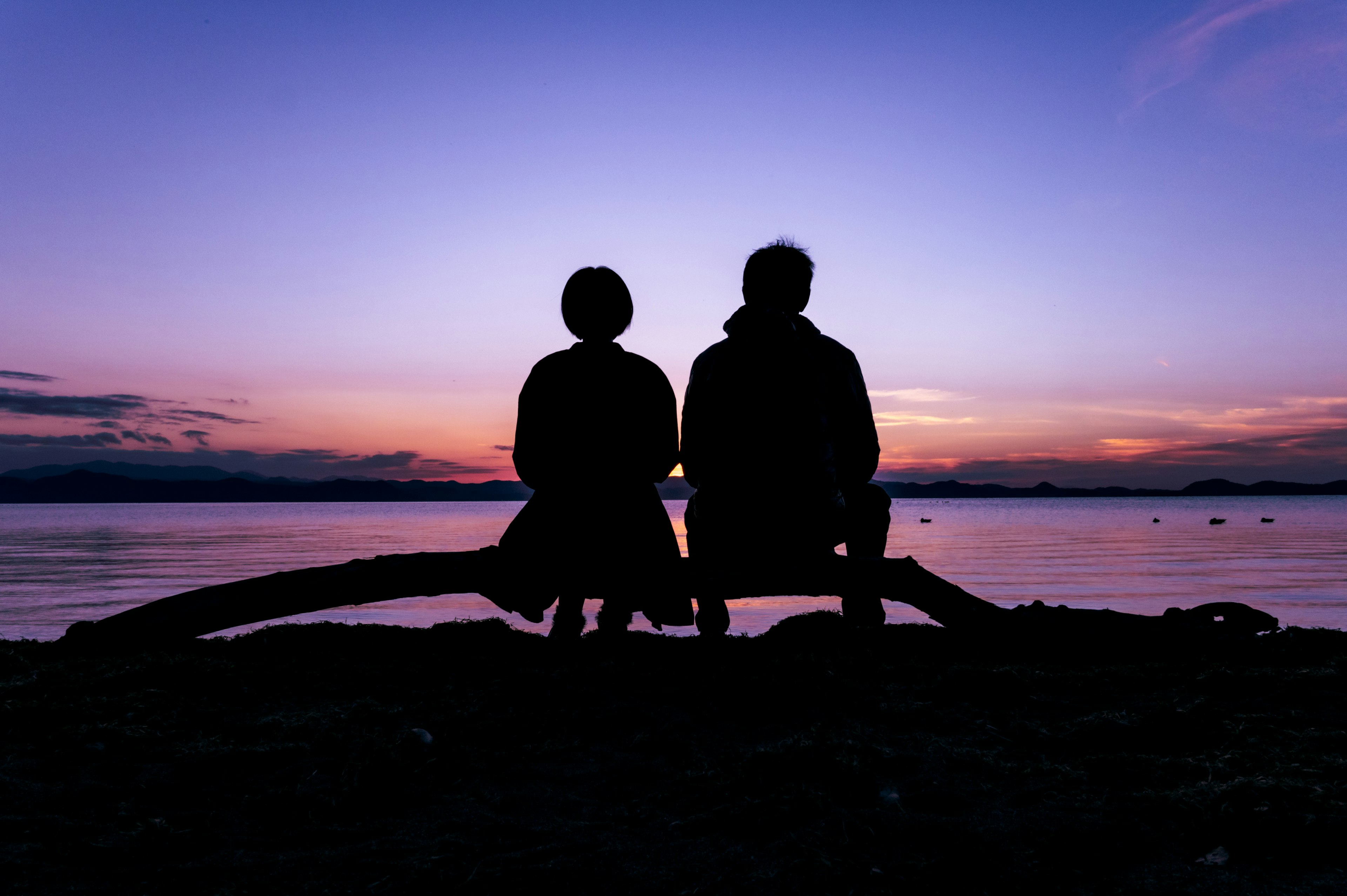 Silhouette of two people watching the sunset over the sea