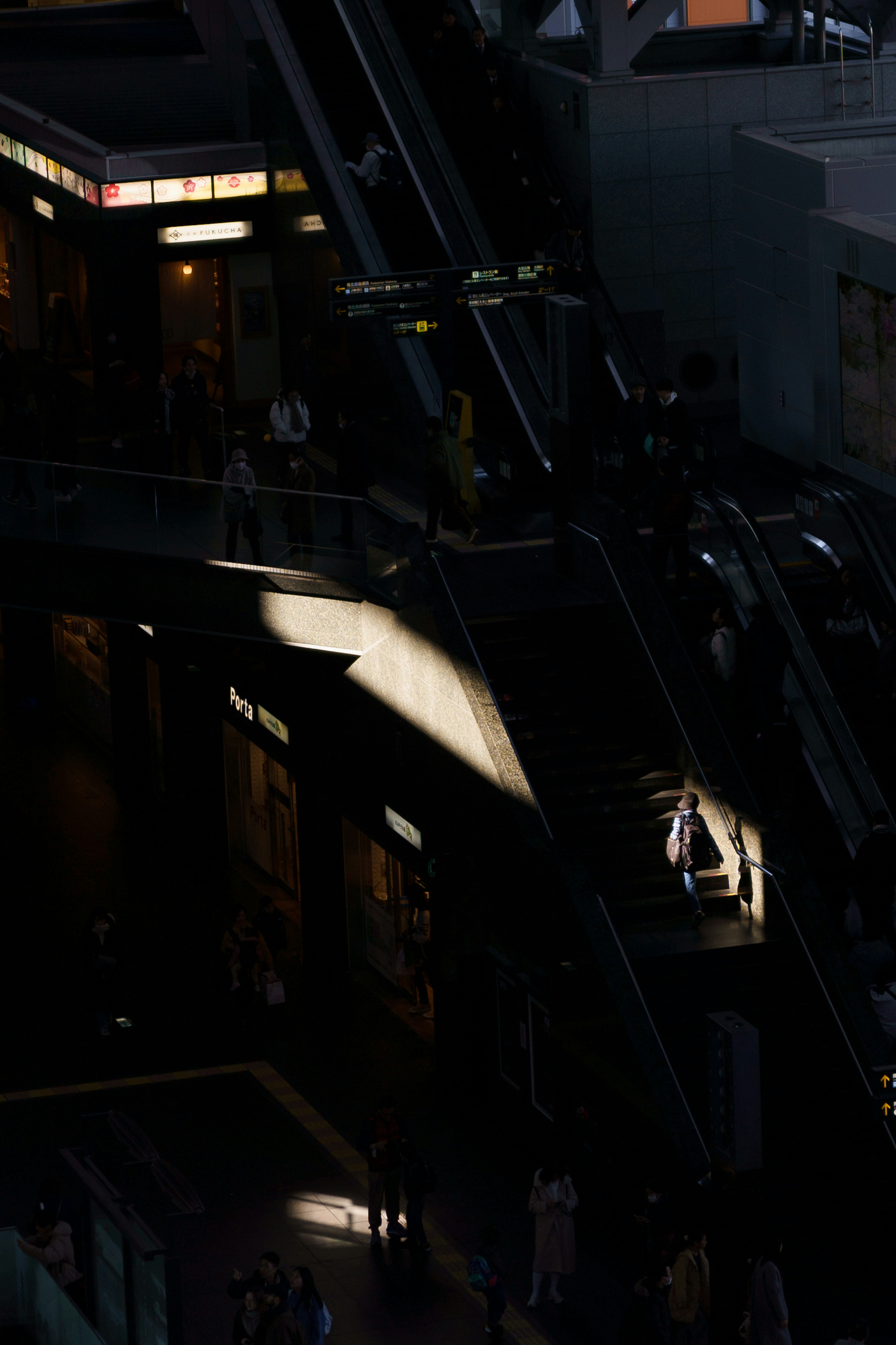 Une scène avec une lumière vive illuminant une zone sombre avec des gens qui marchent