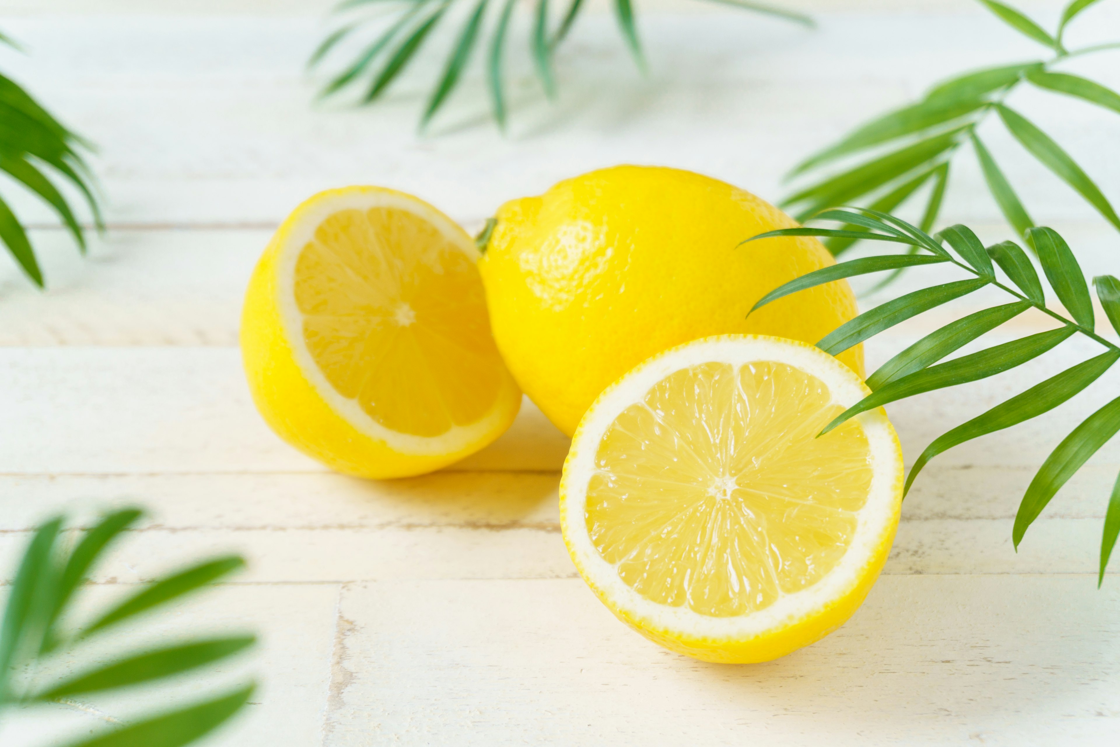 Fresh yellow lemons with green leaves on a wooden surface