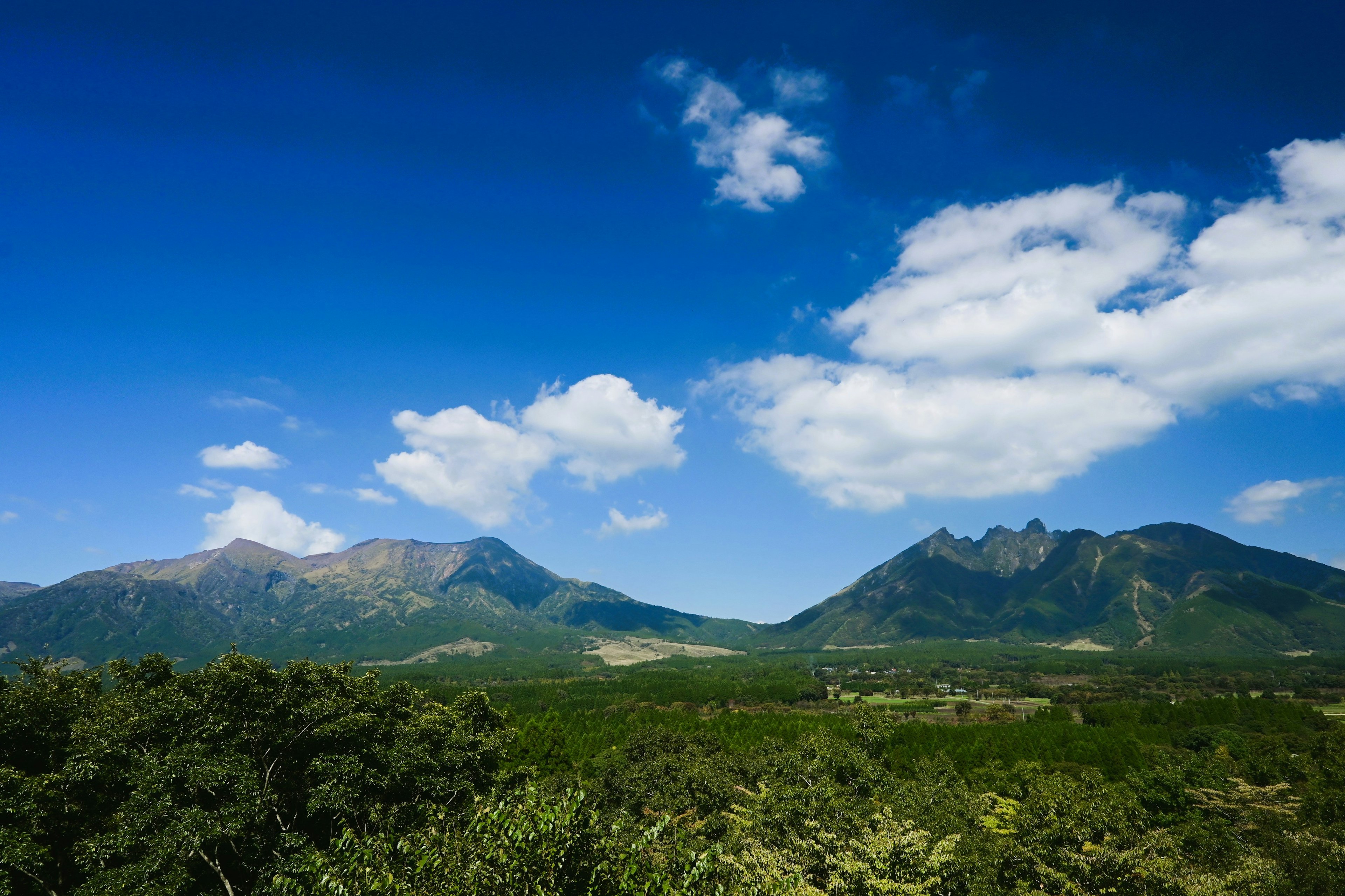 青空と白い雲に囲まれた山々の風景