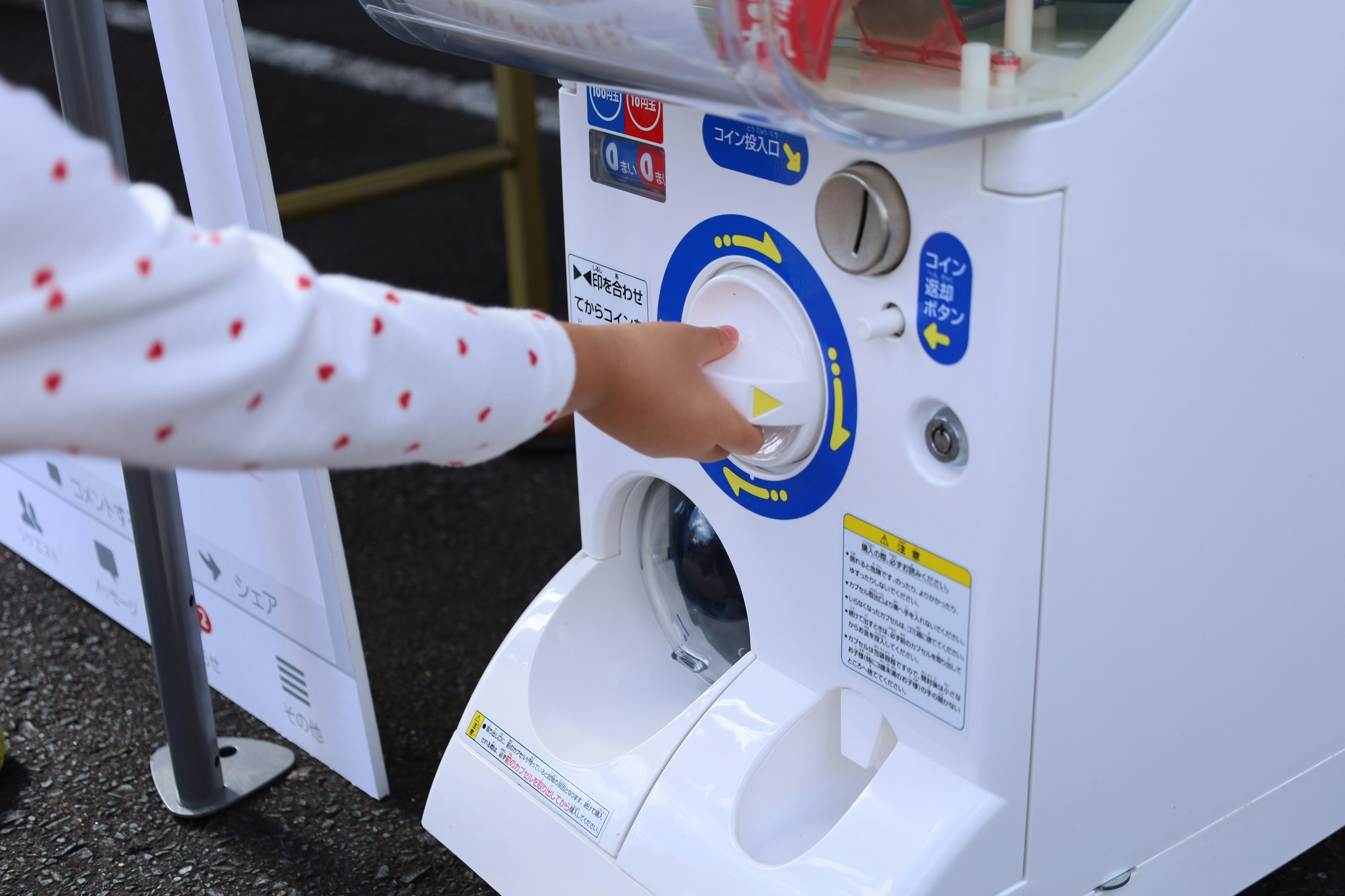 Main appuyant sur le bouton d'une machine à gacha blanche