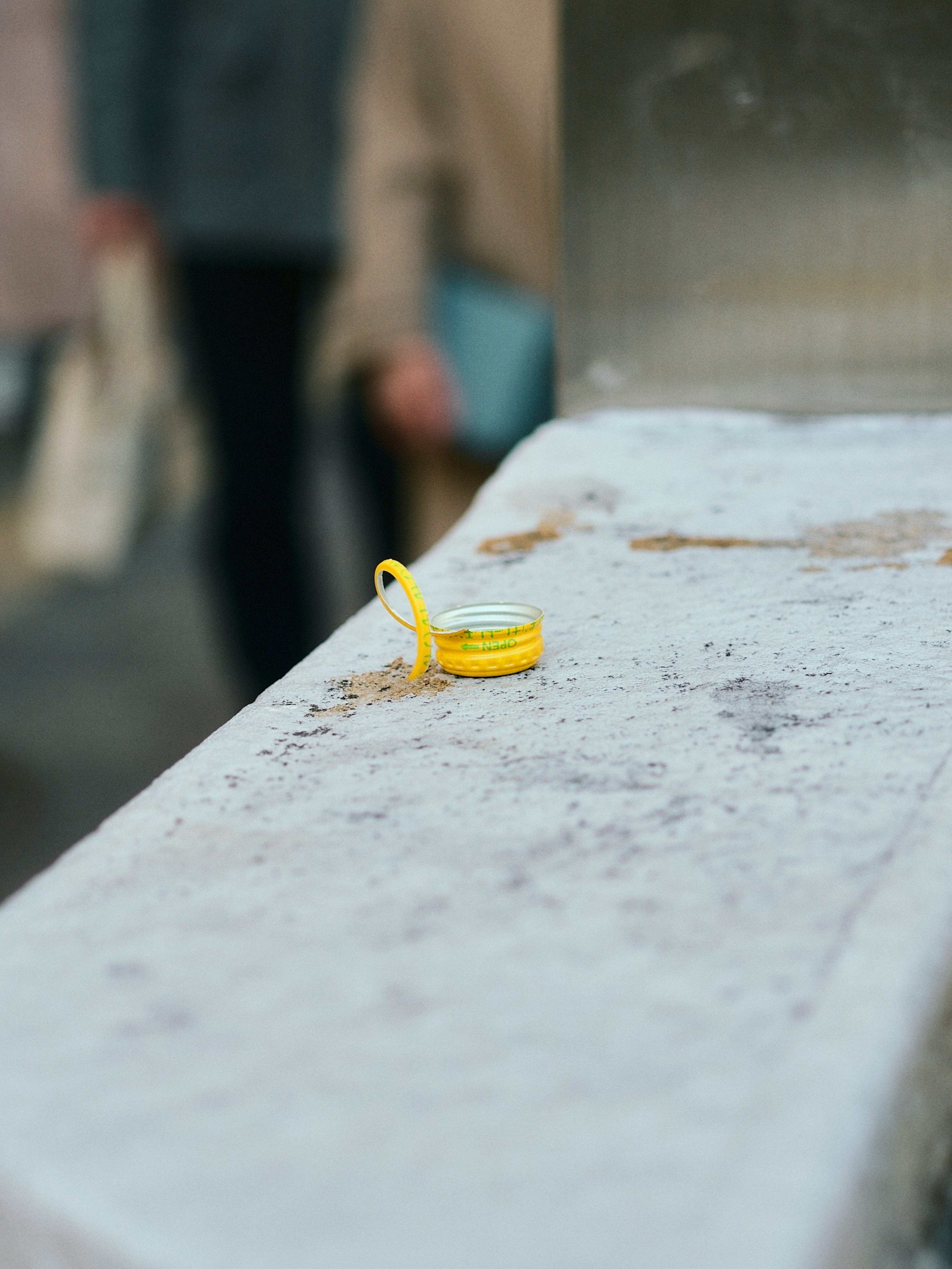 A yellow ring placed on white concrete with blurred figures in the background