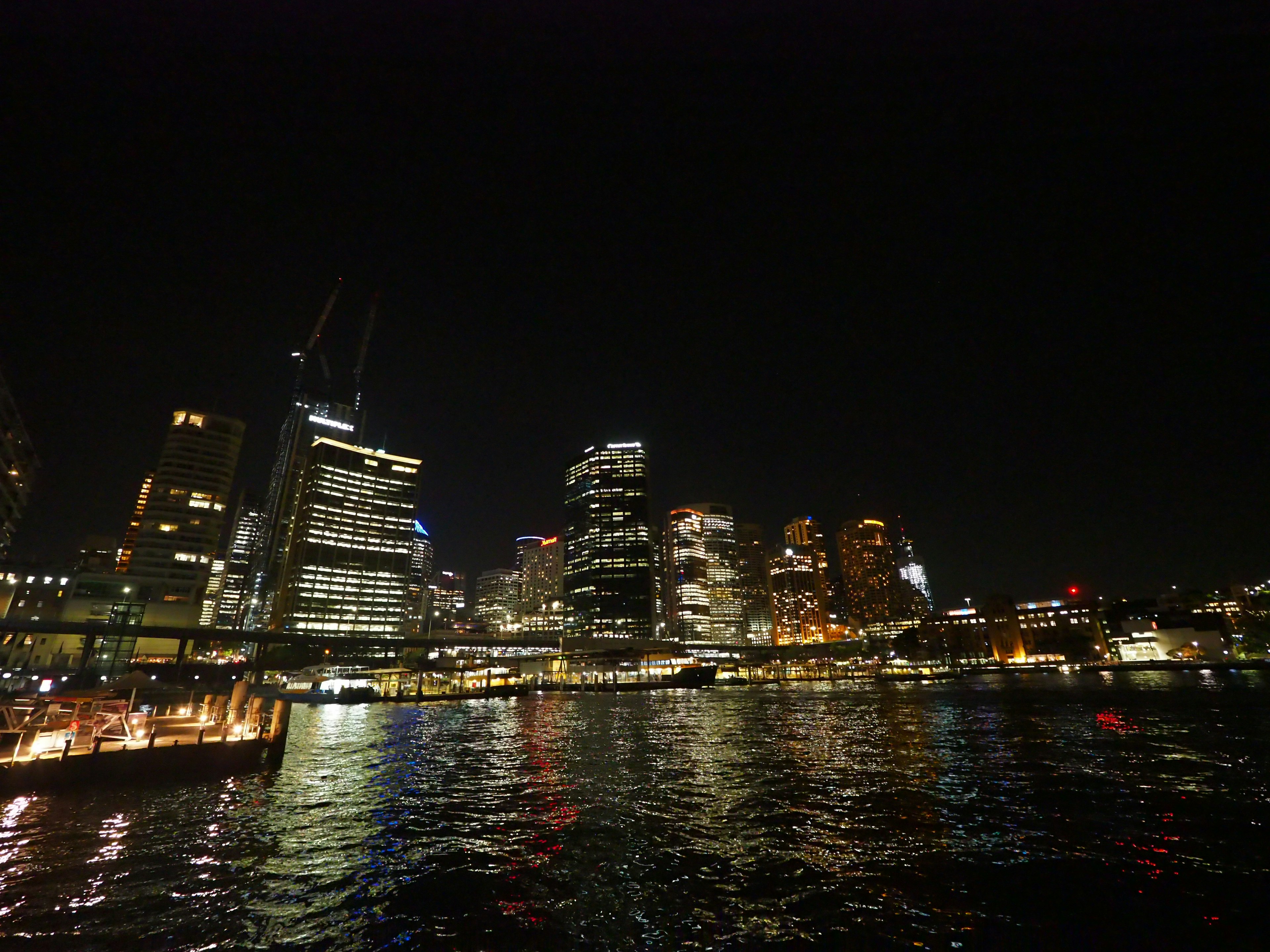 Skyline di Sydney di notte con edifici illuminati e acqua riflettente