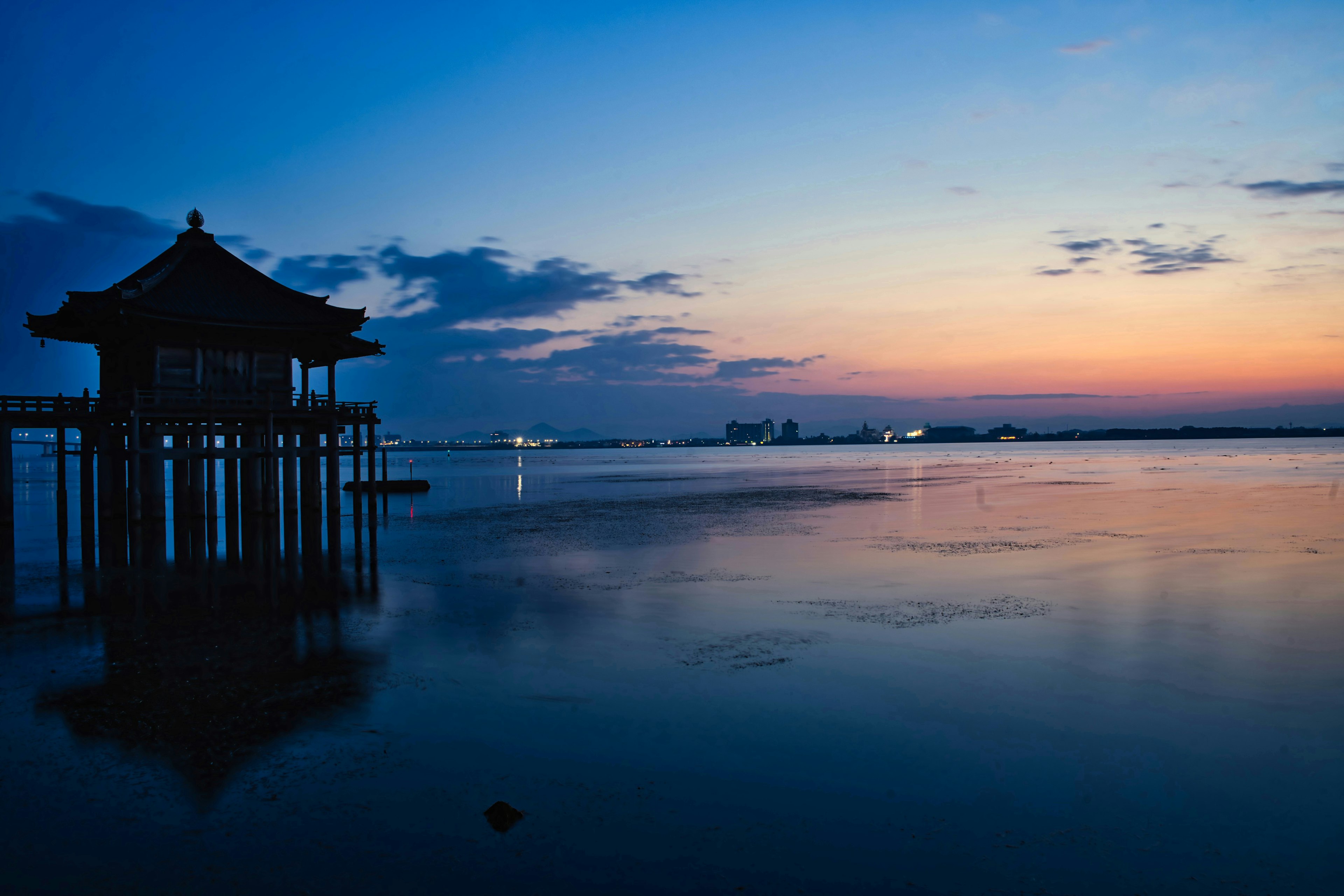 美しい夕焼けの中、海に映る伝統的なパビリオン