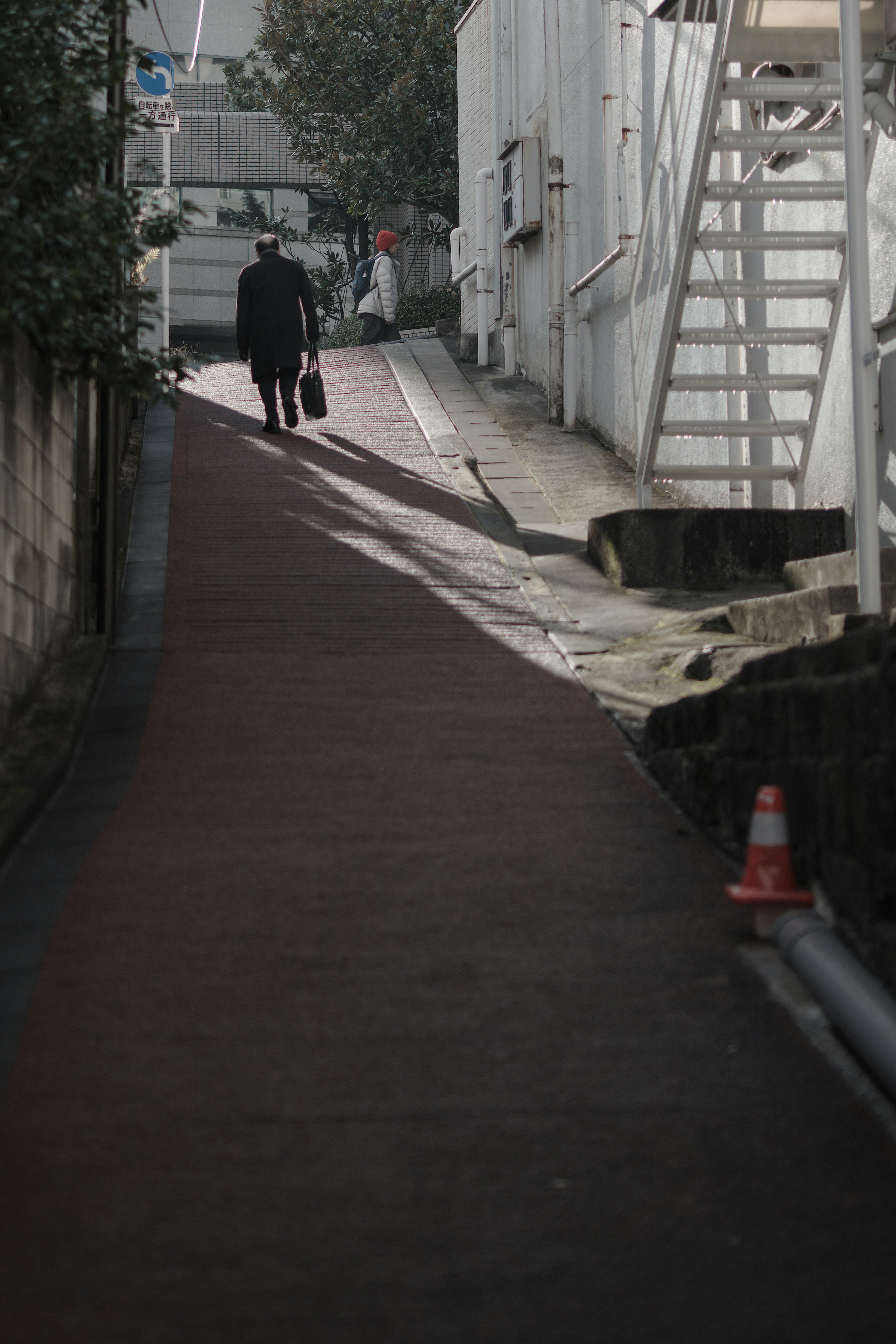 Eine Person, die einen schmalen Weg entlanggeht, mit Gebäuden im Hintergrund, die eine düstere Atmosphäre schaffen