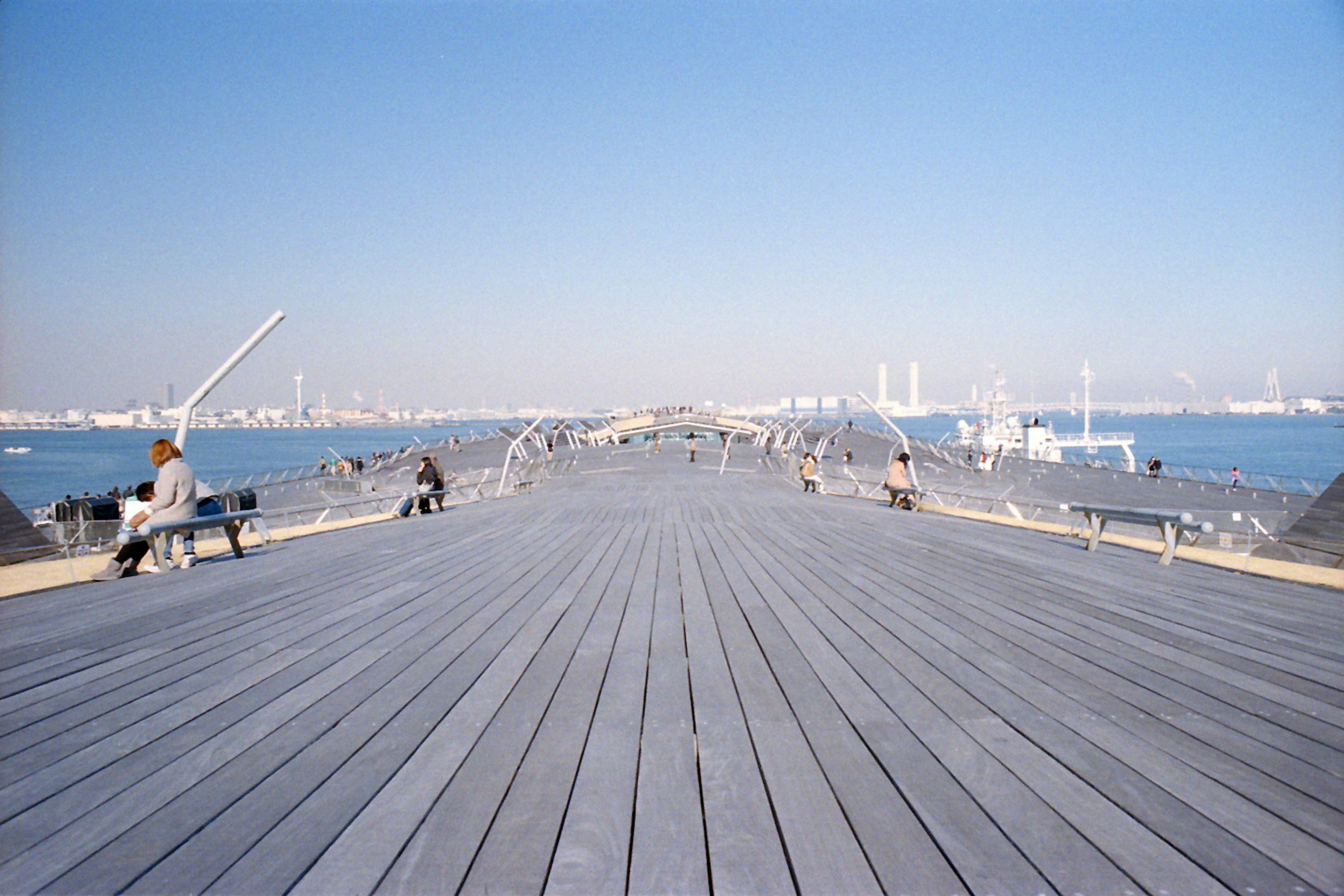 Holzdeck, das sich unter einem klaren blauen Himmel zum Meer erstreckt