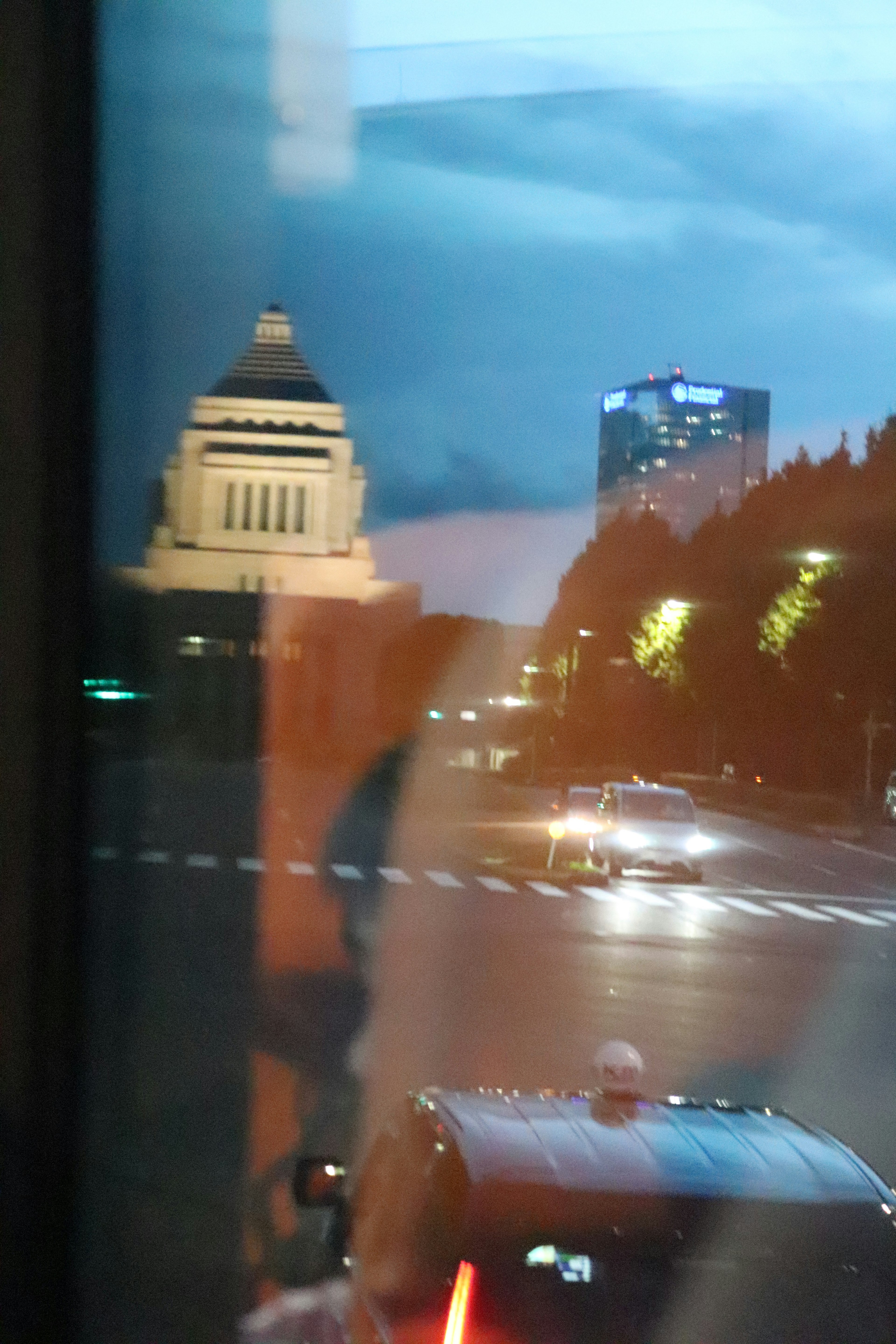 夜の街並みと国会議事堂の外観が映る窓越しの風景