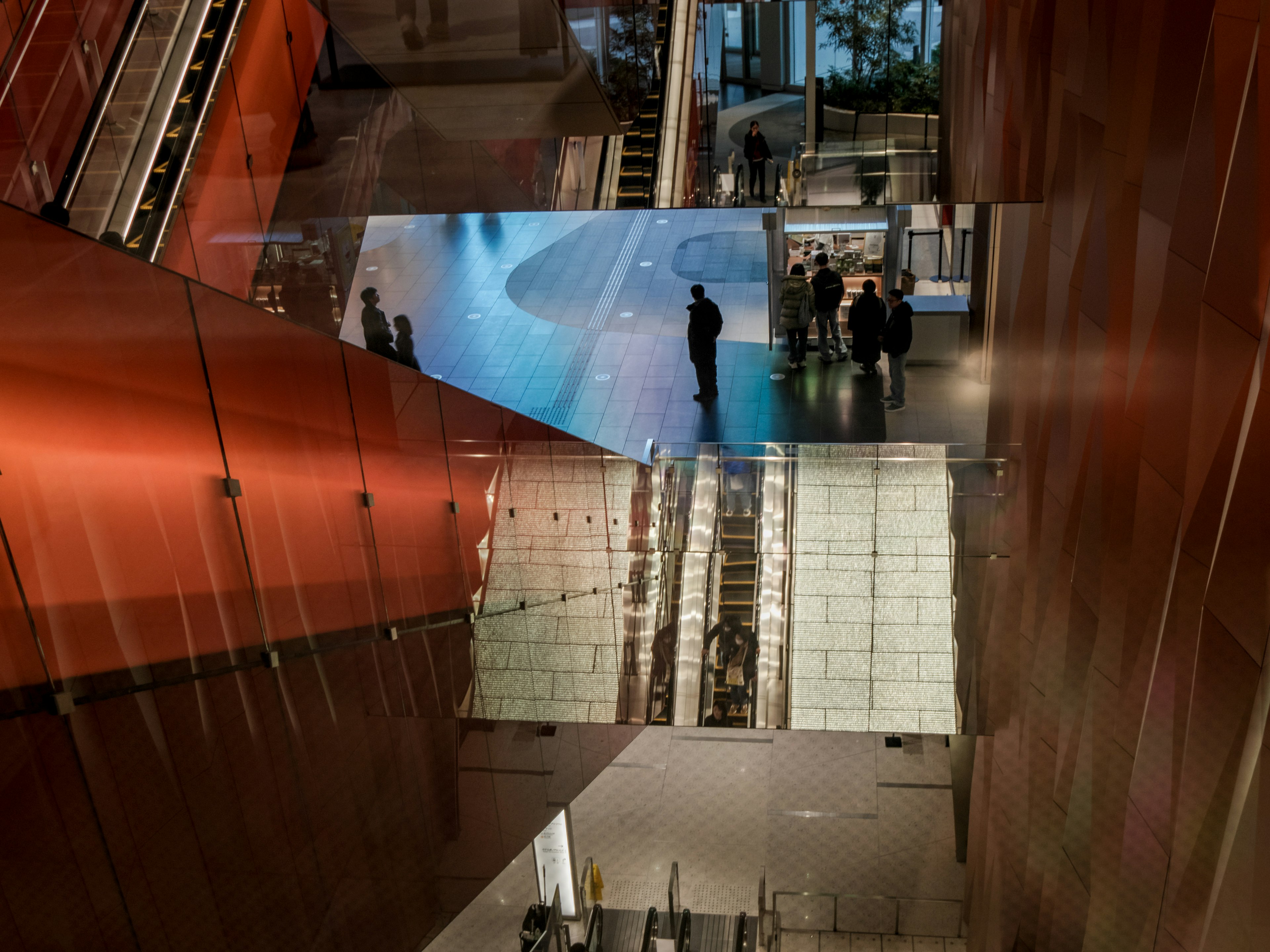 Interior de un edificio moderno con personas en movimiento y reflejos en superficies de vidrio