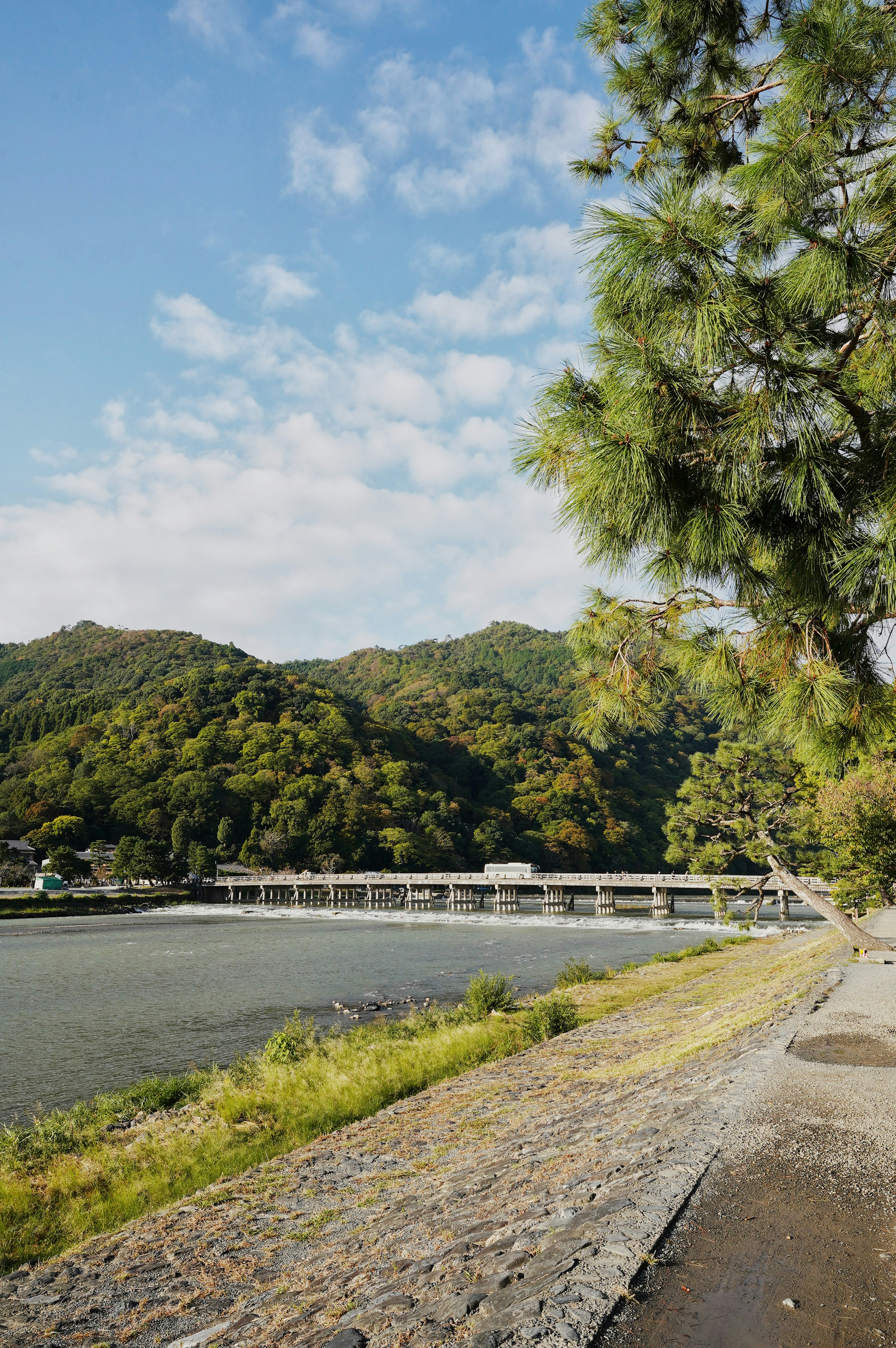 Scenic view of a river and bridge surrounded by green hills and blue sky