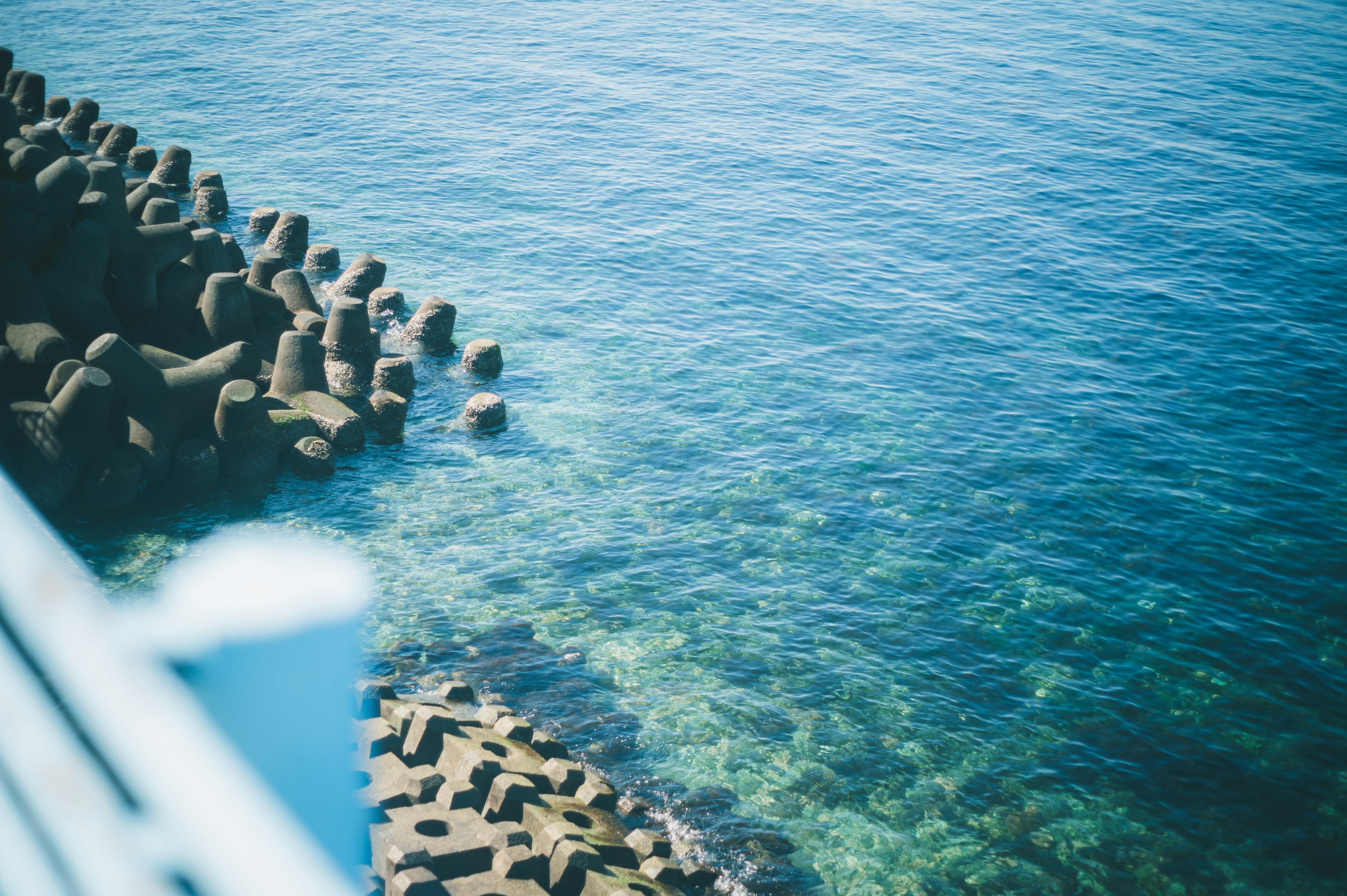 Blue sea with clear water and concrete tetrapods along the shore