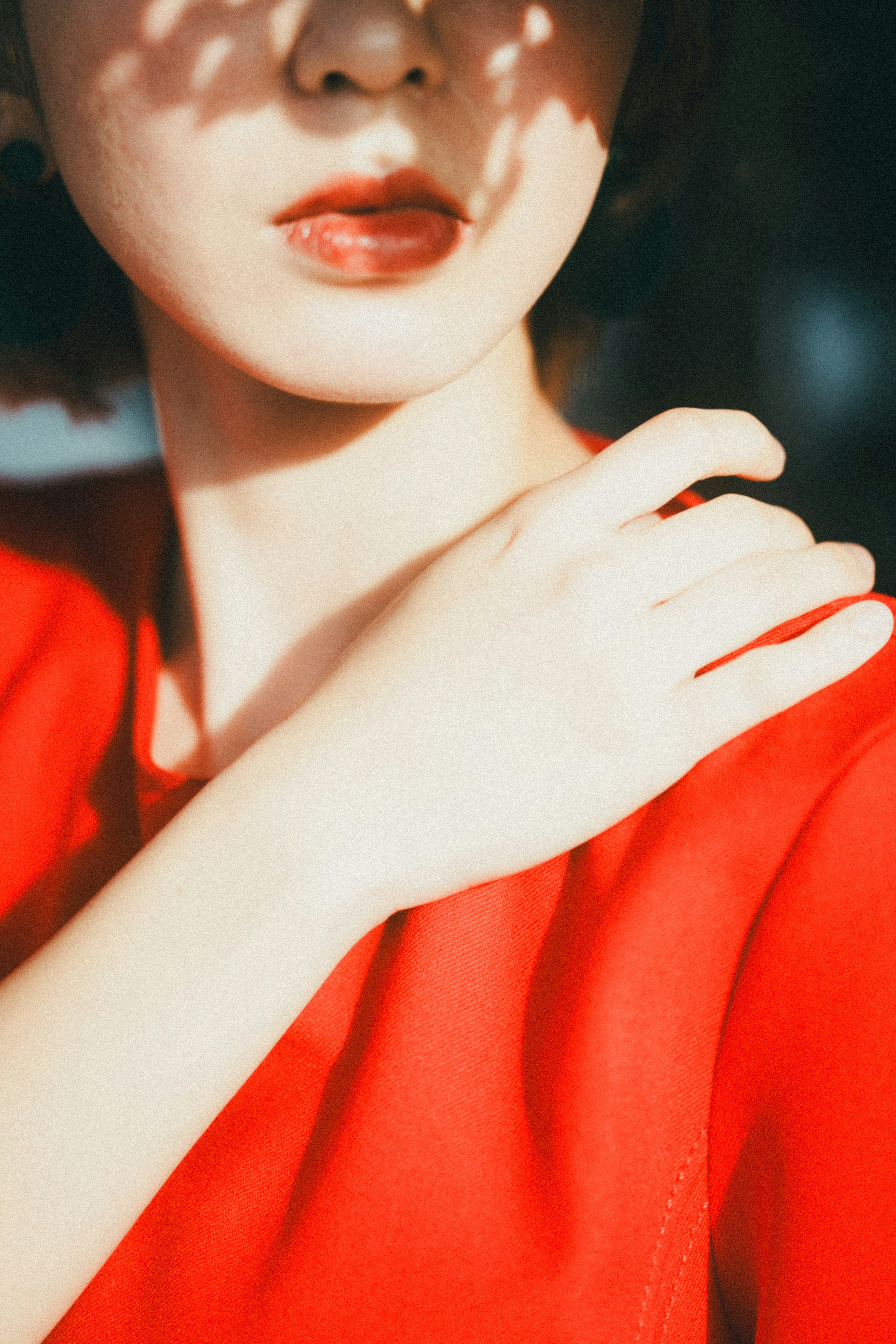 Close-up of a woman in a red dress highlighting her shoulder and lips