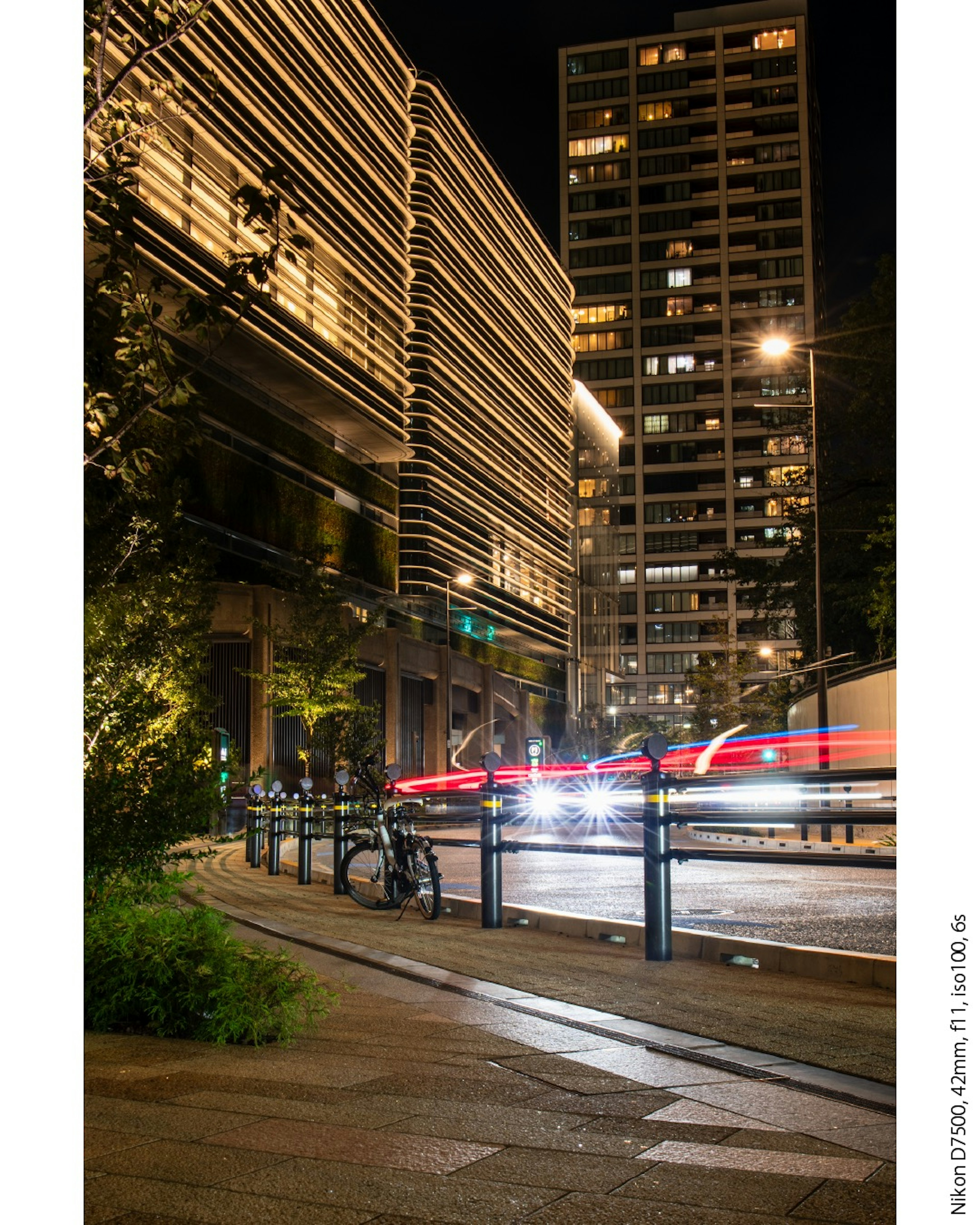 Cityscape at night with flowing car lights and modern buildings