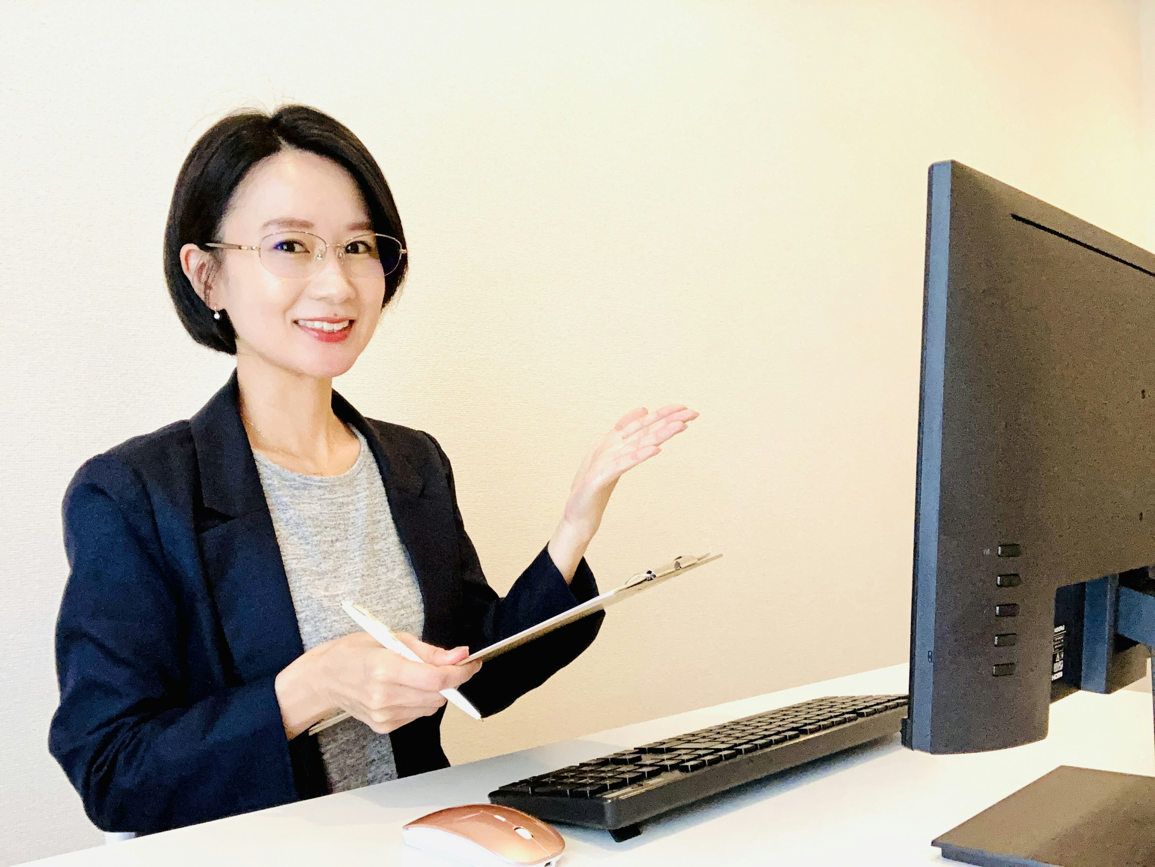 Una donna sorridente che gesticola con la mano a una scrivania con un computer