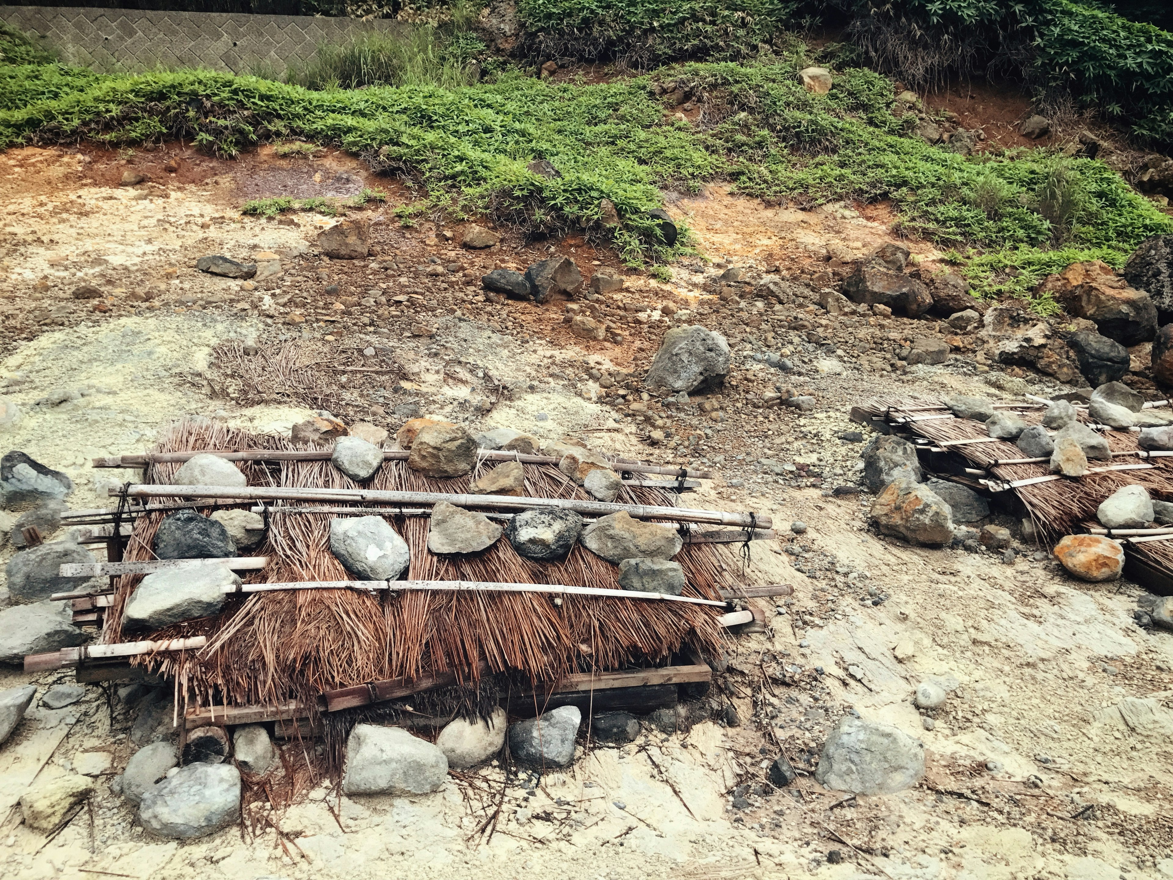 Struktur tradisional yang terbuat dari batu dan kayu terlihat di pantai berpasir