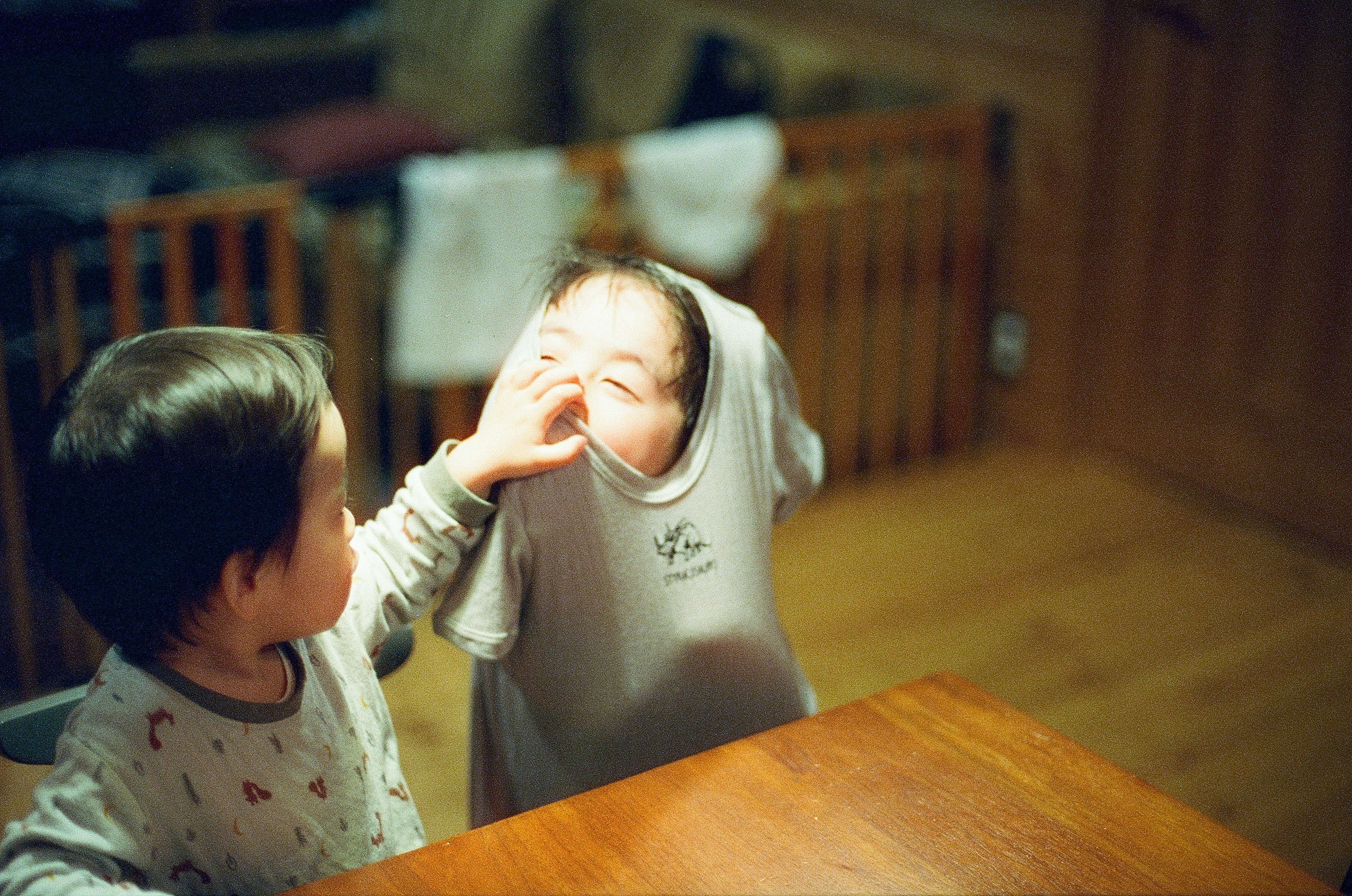 A child attempting to put a shirt on another child