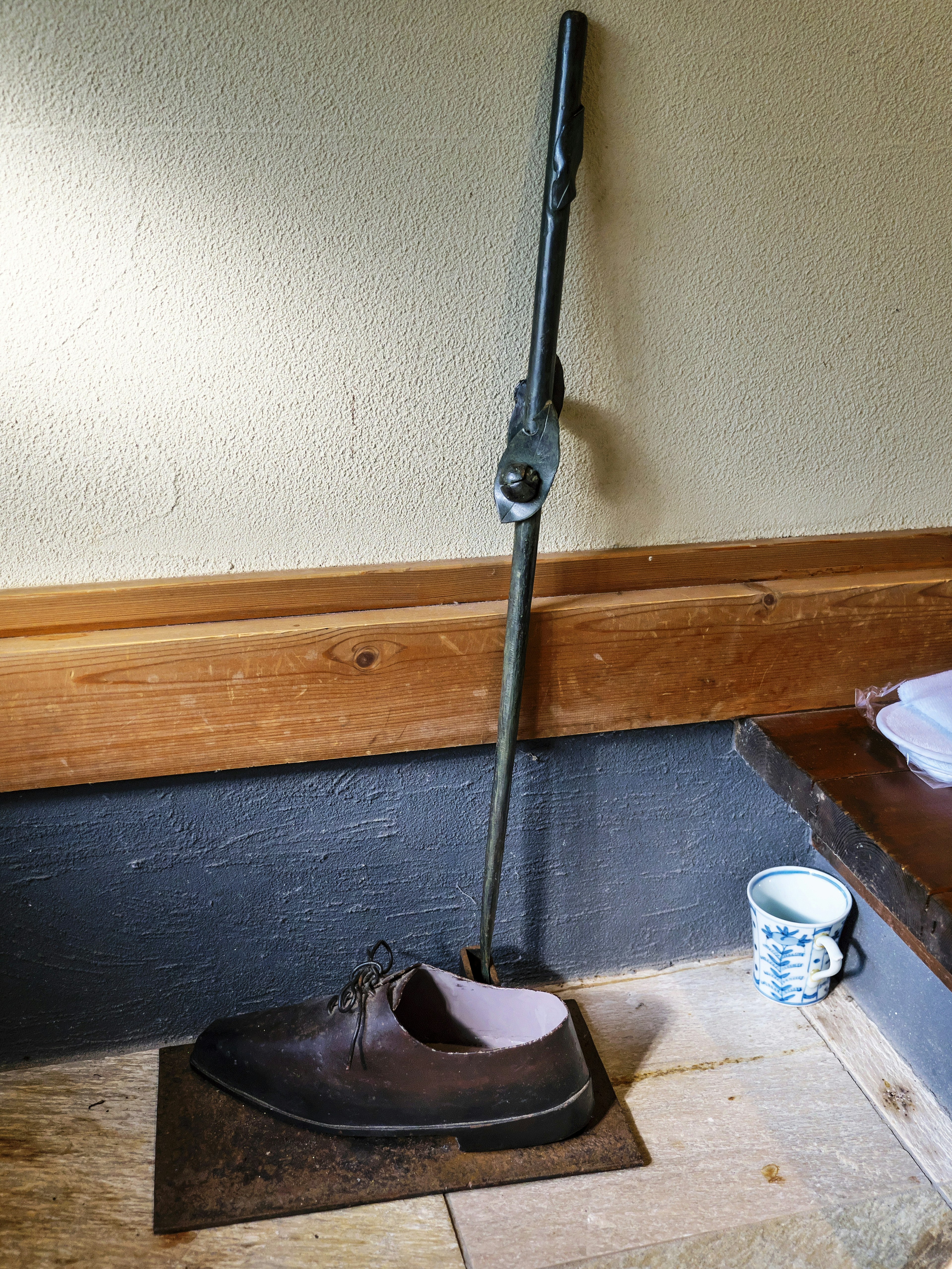 Metal shoehorn in the shape of a shoe leaning against the wall