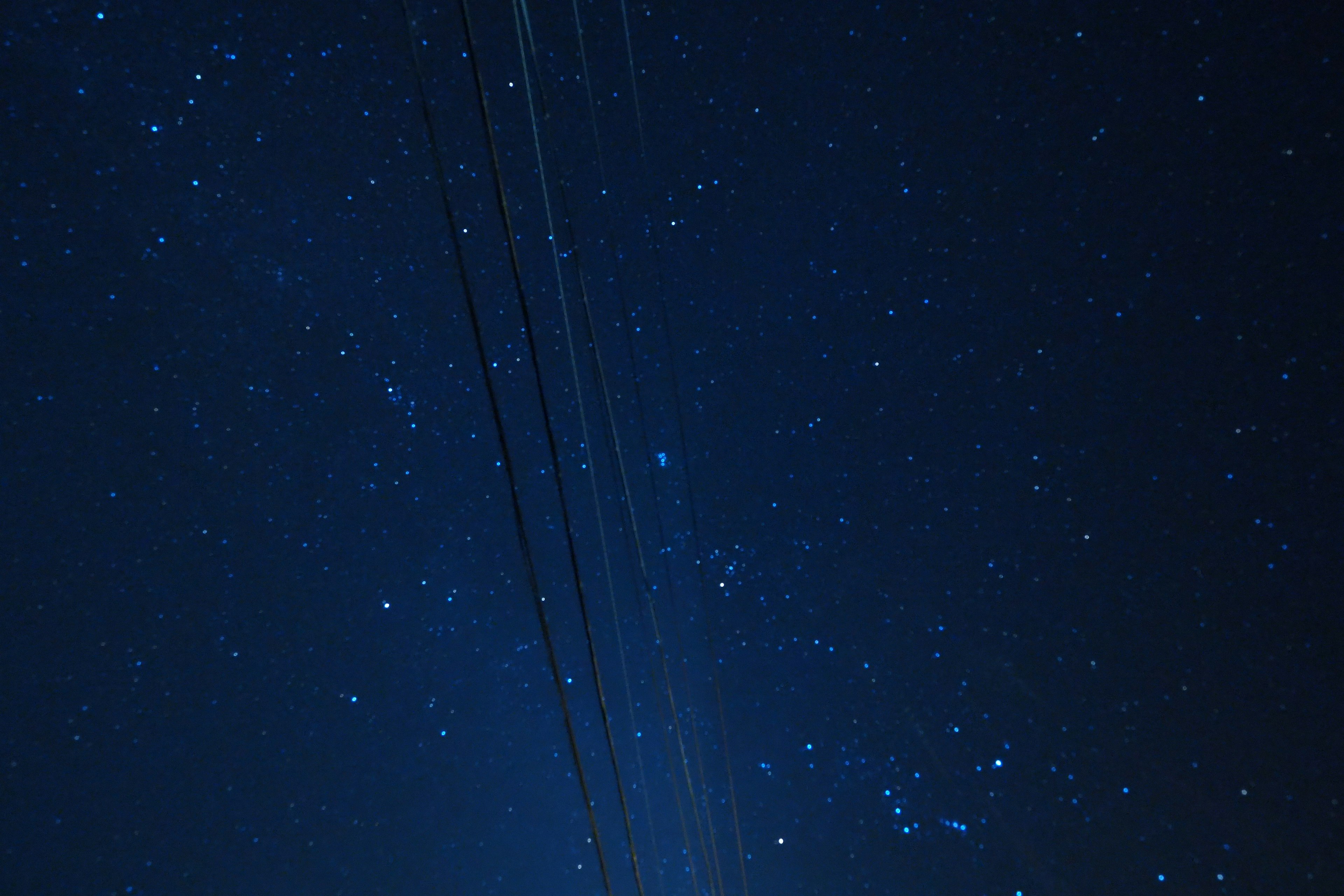 Cielo nocturno oscuro lleno de estrellas y líneas eléctricas