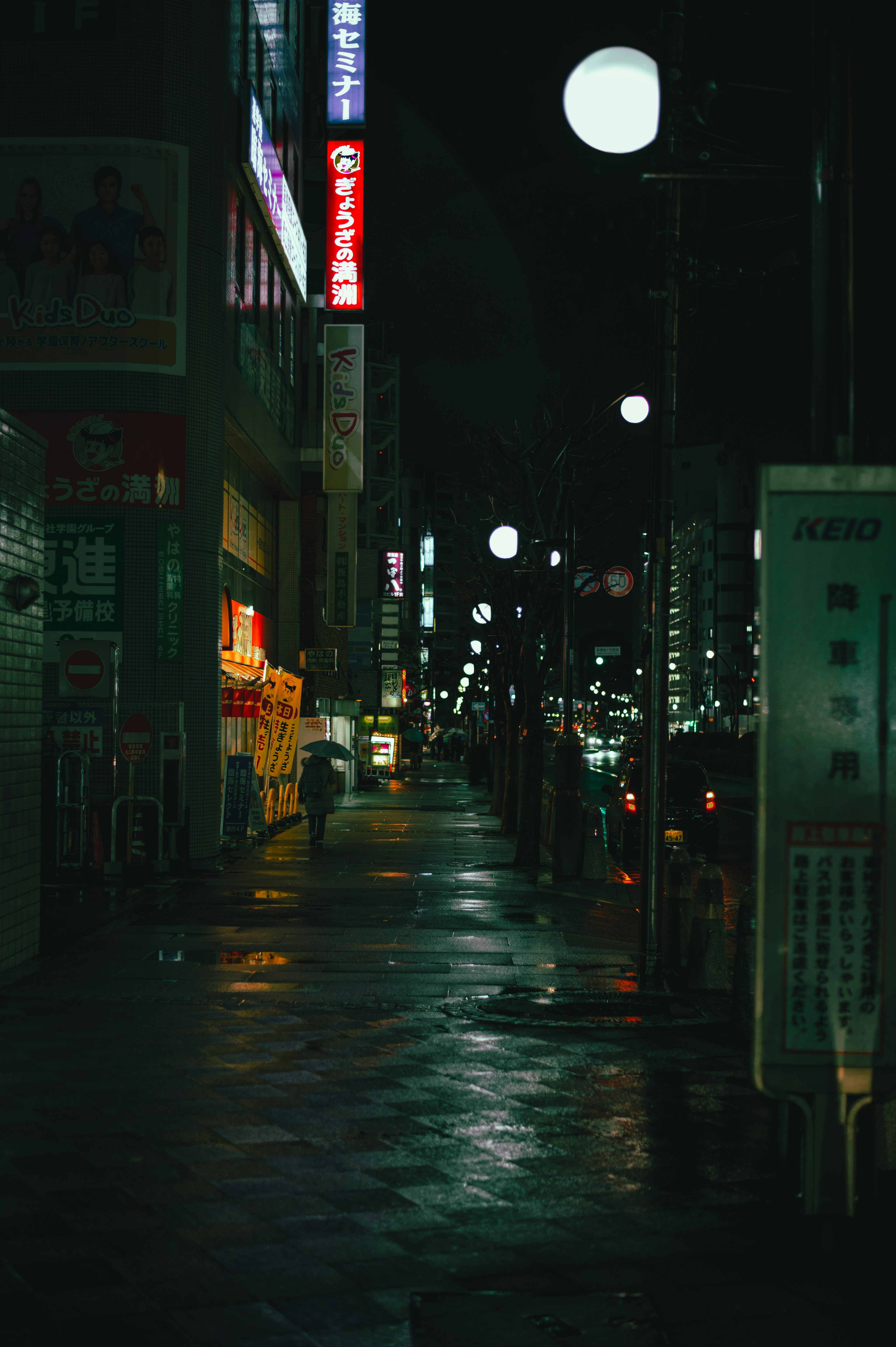 Sidewalk illuminated by streetlights and signs at night