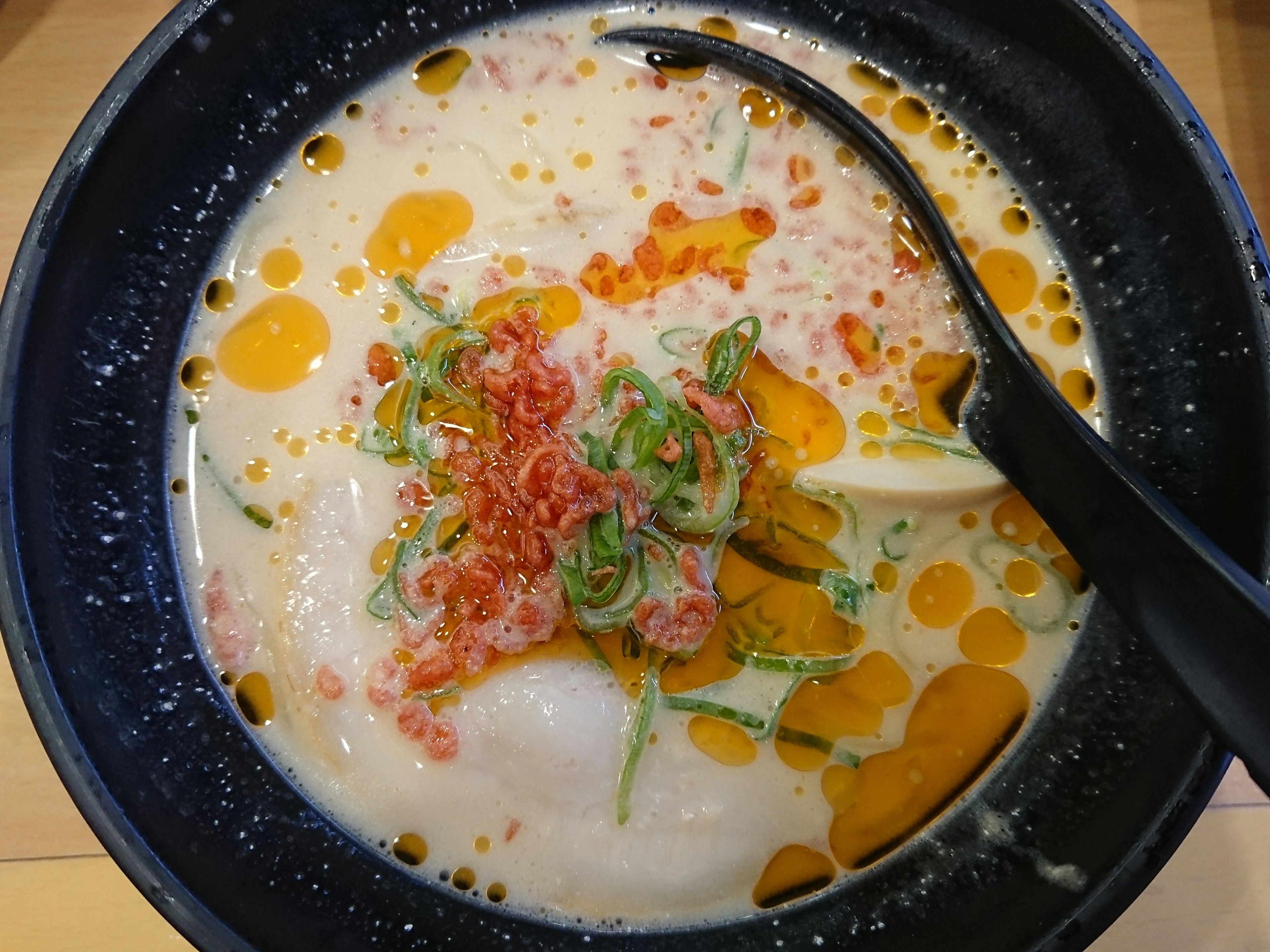 Ramen in brodo cremoso guarnito con cipollotti e uova di pesce