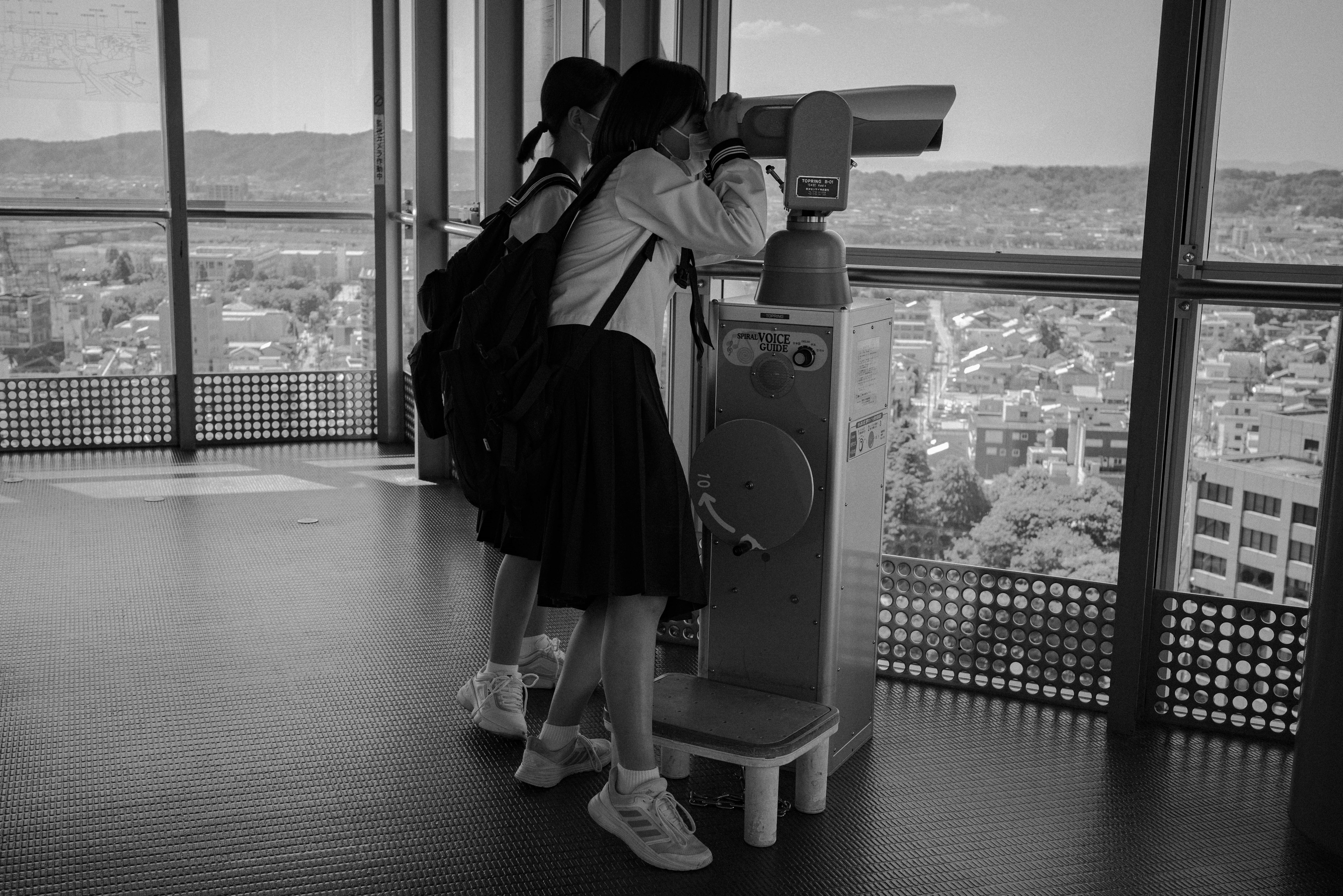 Two students looking through a telescope at an observation deck