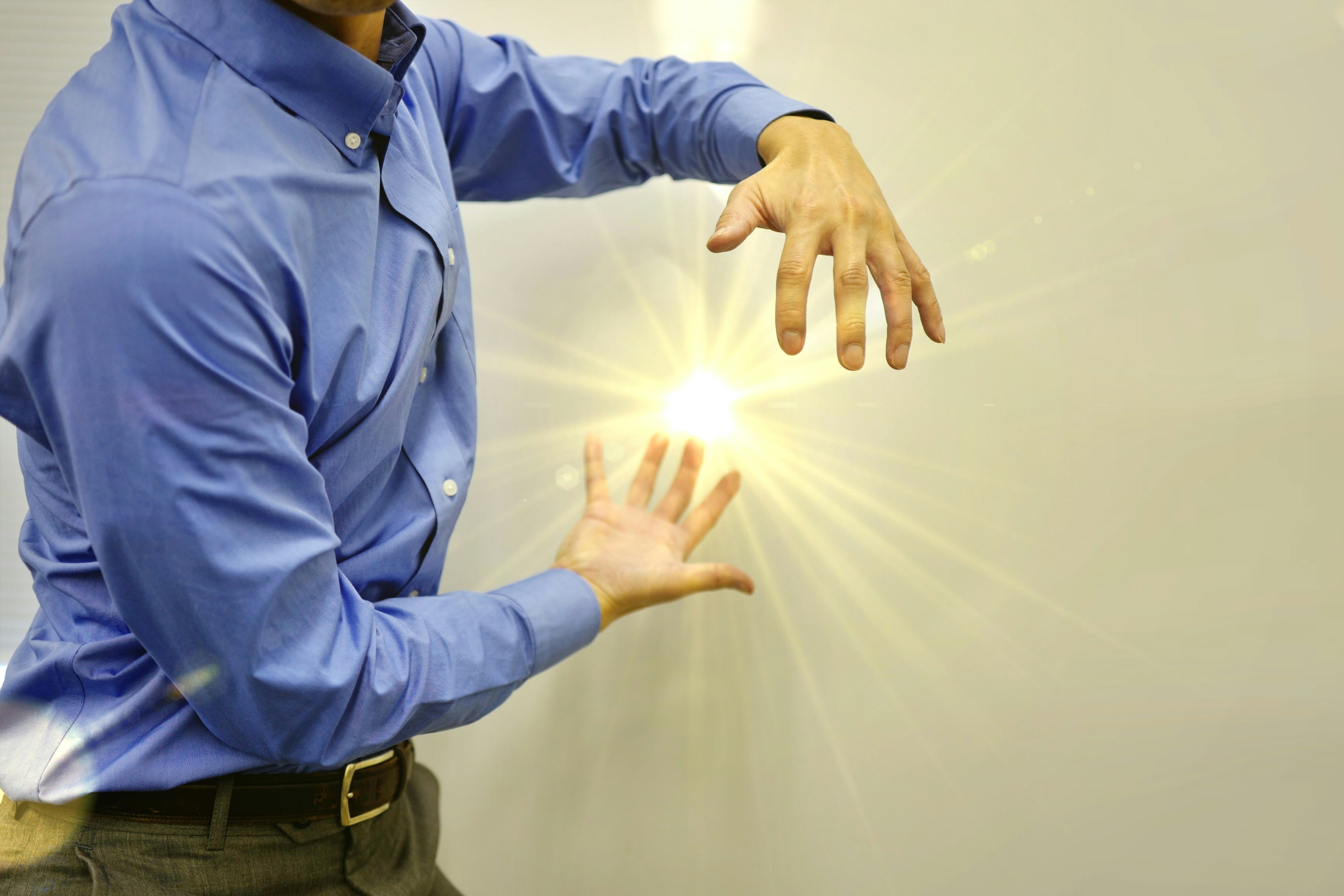 Homme en chemise bleue écartant les mains avec une lumière brillante