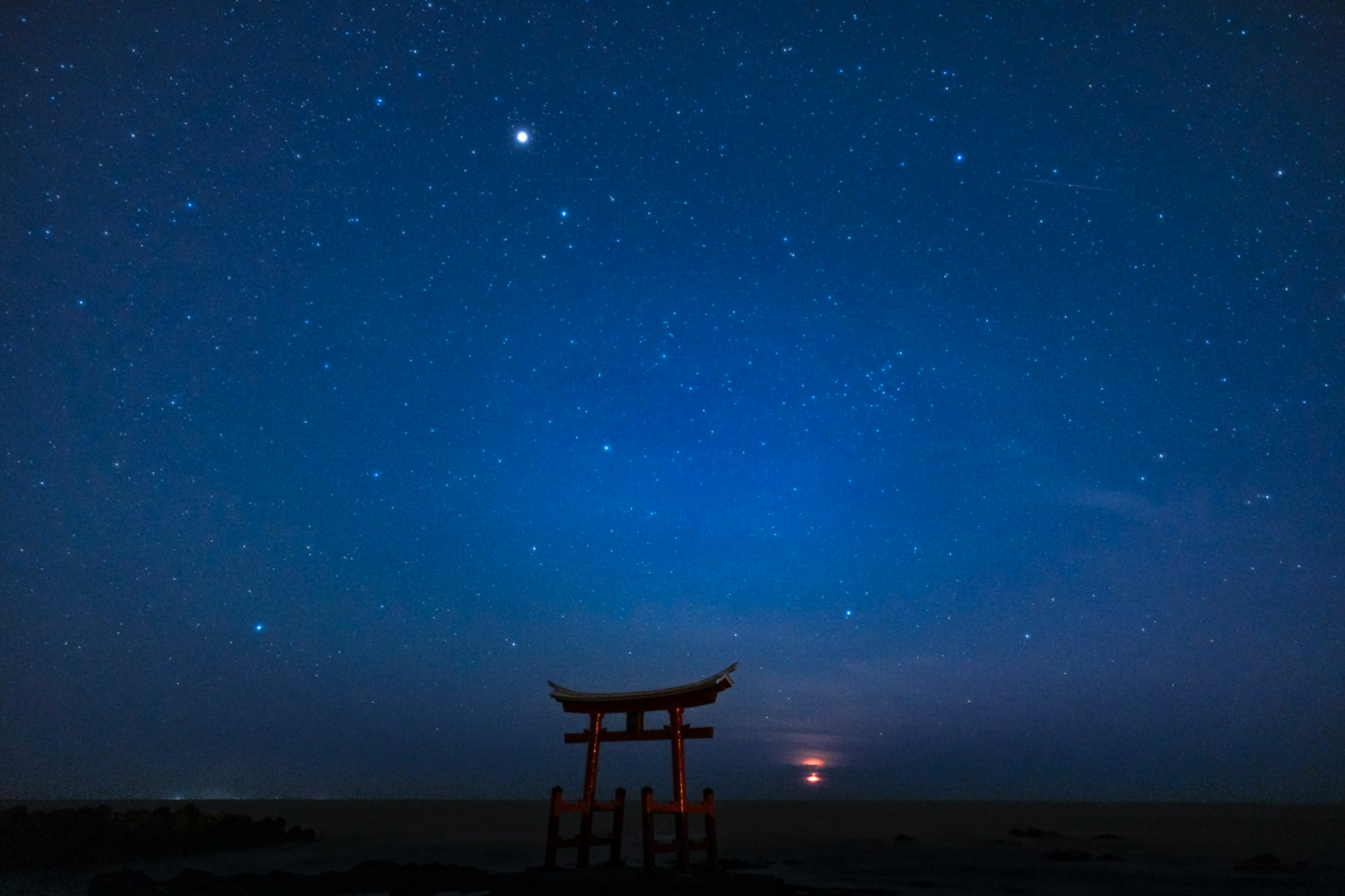 Cổng torii dưới bầu trời đầy sao với biển yên tĩnh