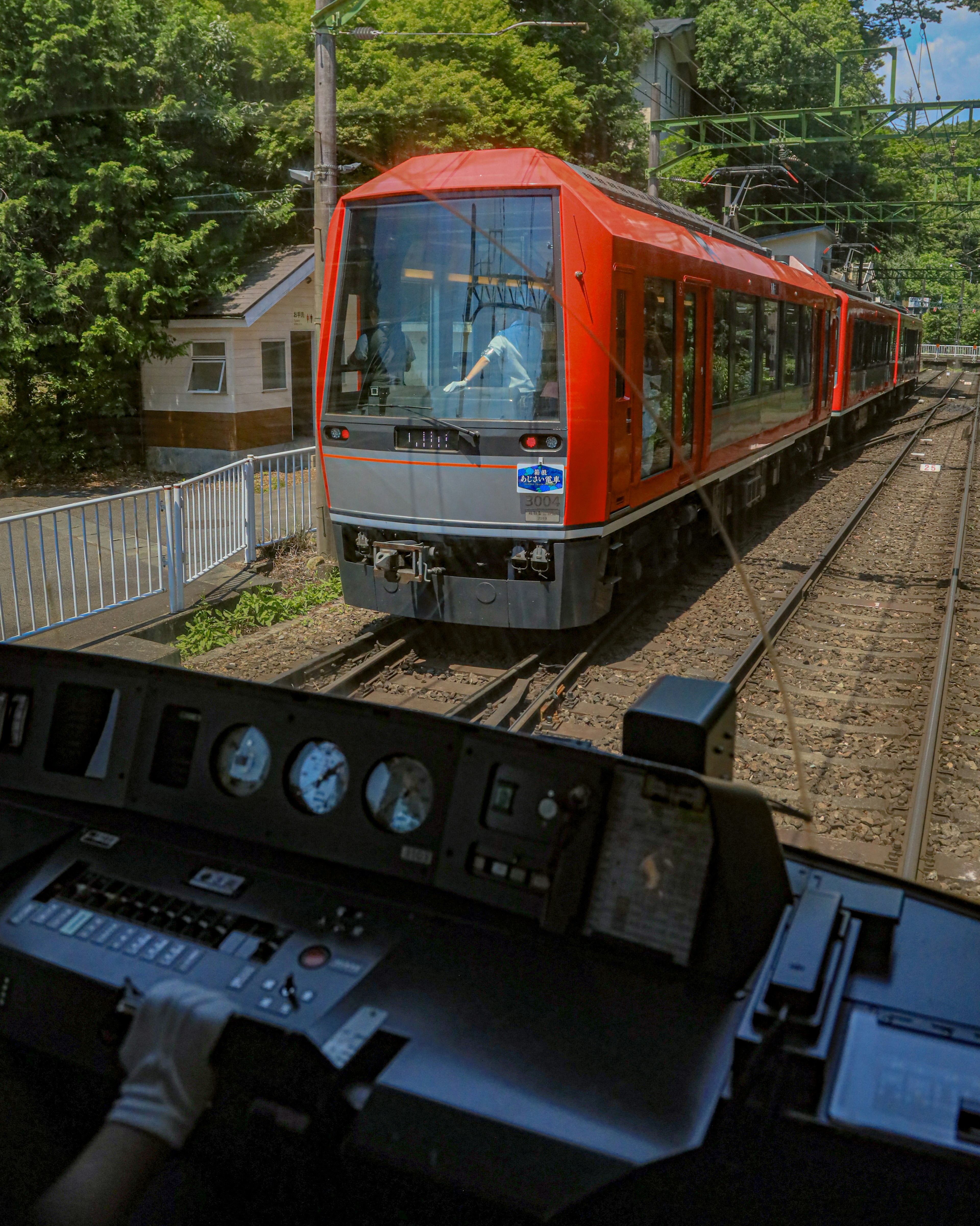 運転席から見た赤い電車が線路を走る風景