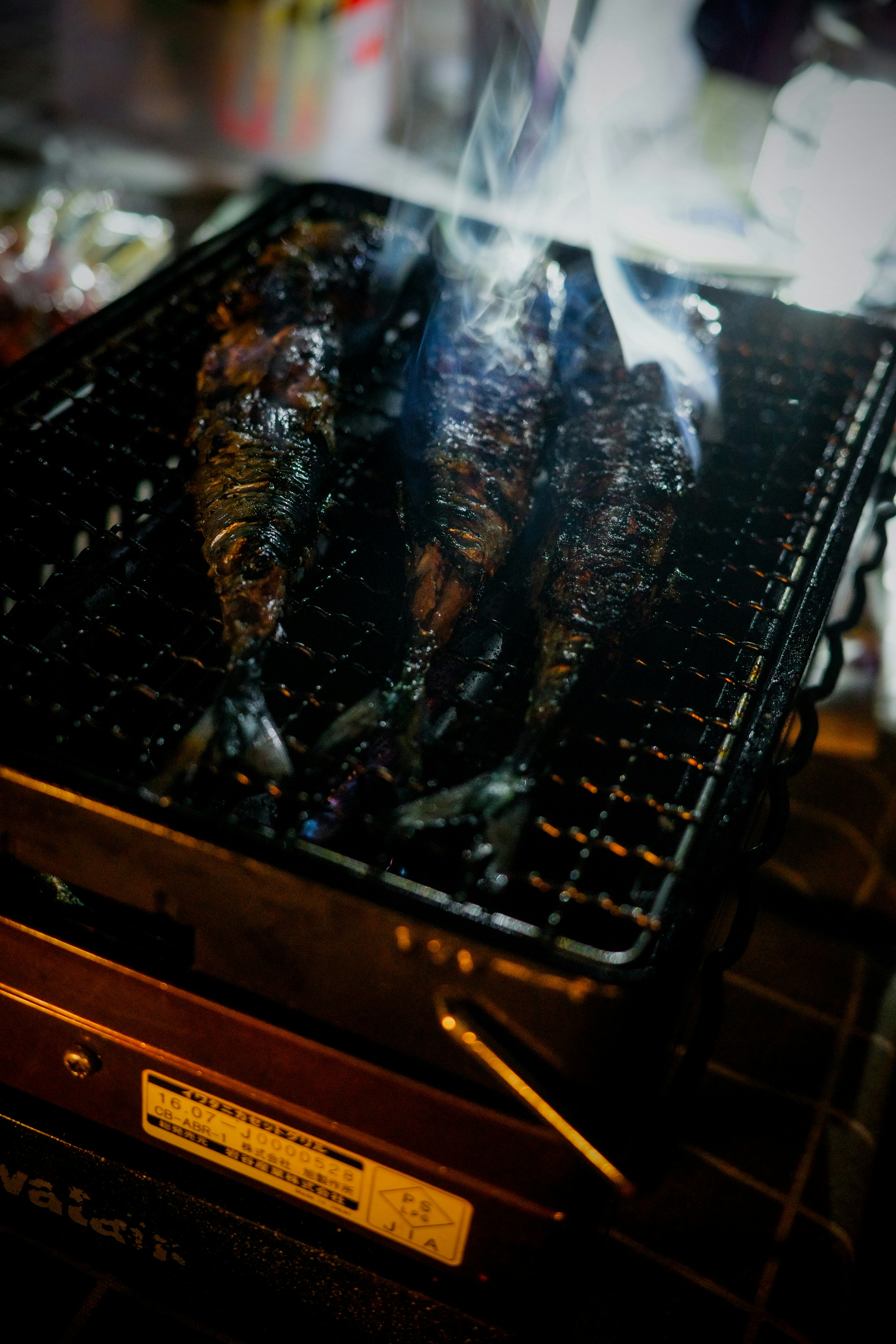 炭火で焼かれた魚の串焼きがグリルの上に置かれている