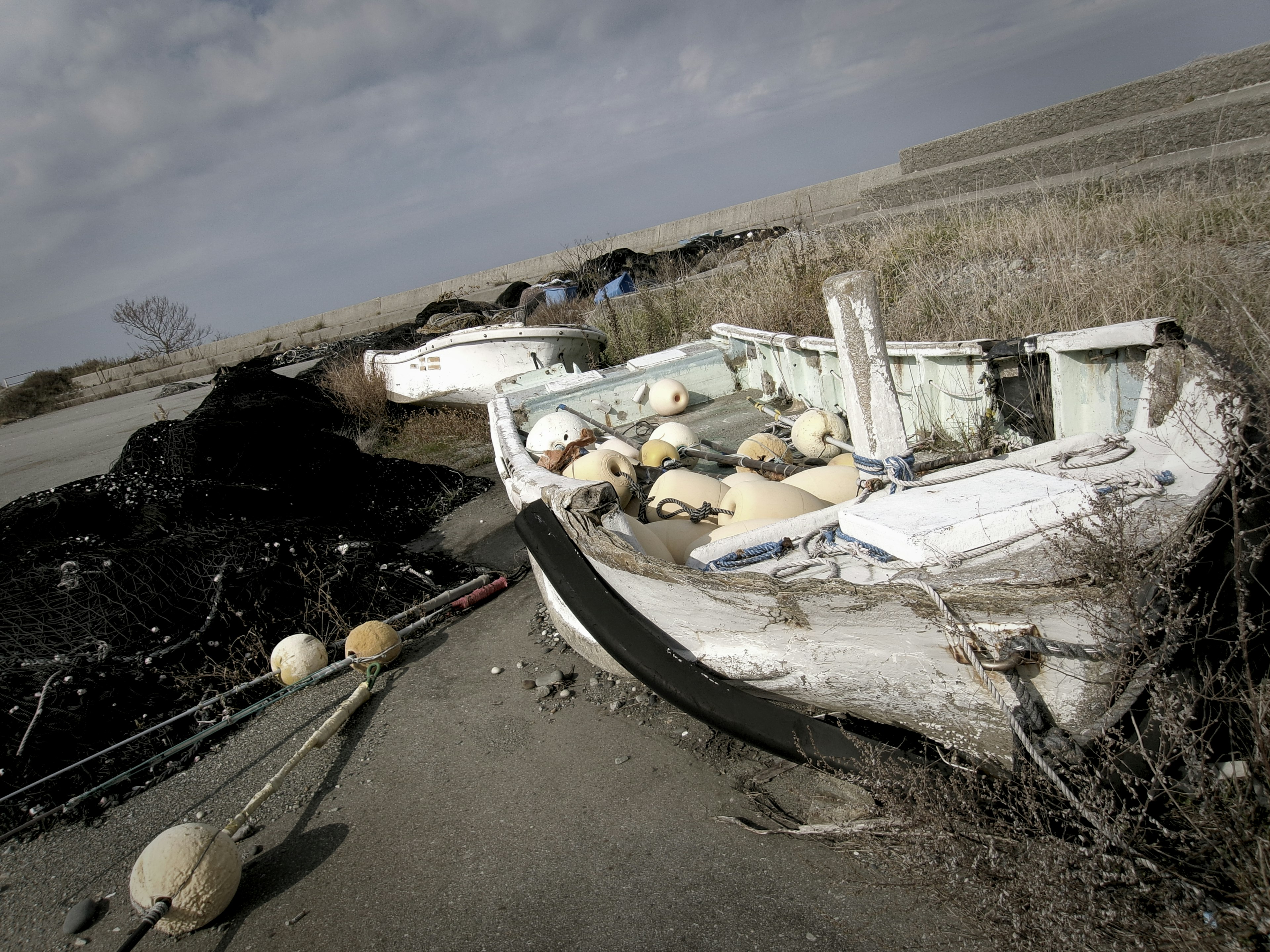 Ein altes Fischerboot liegt auf dem Gras mit verstreuten Bojen