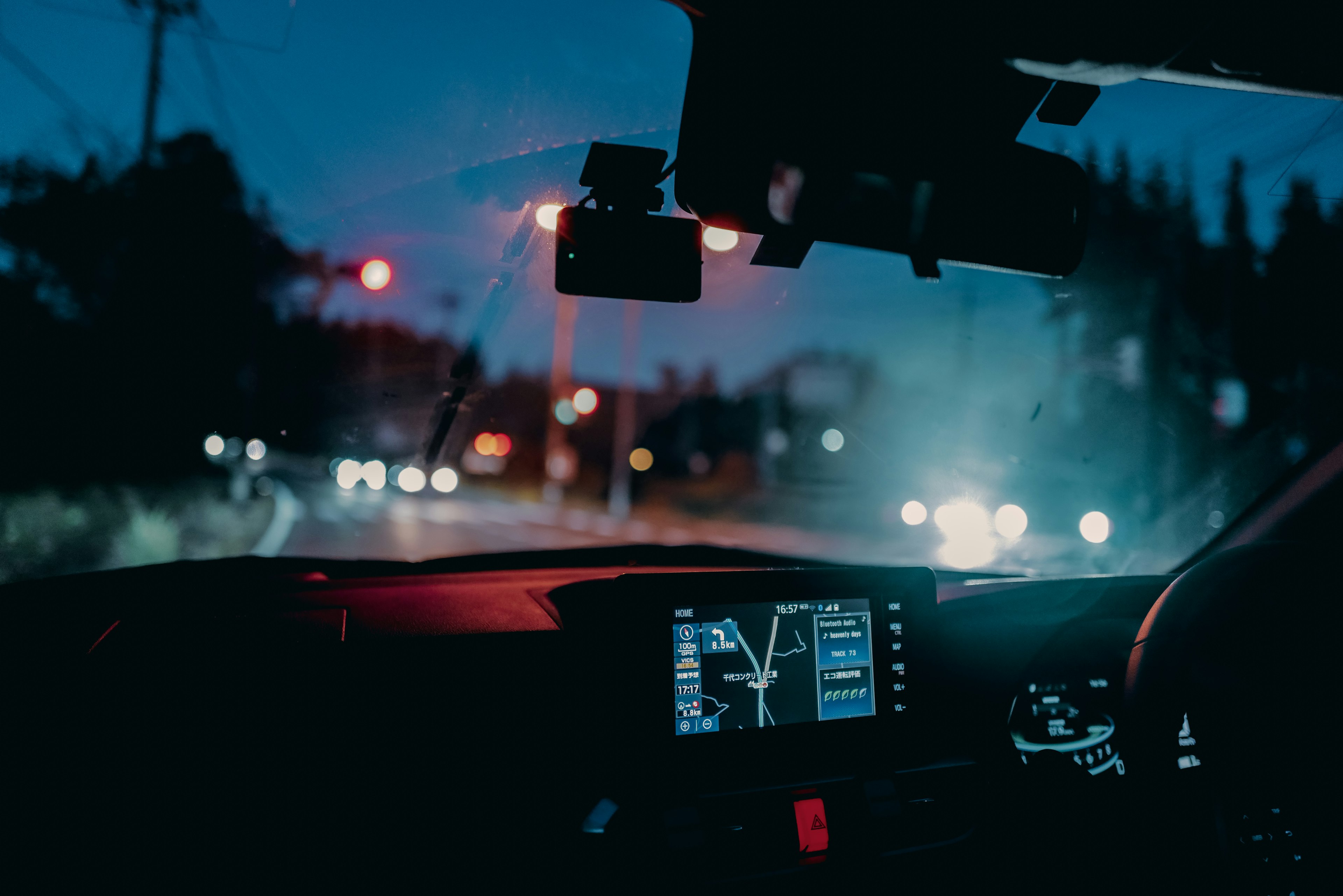 View from inside a car at night with a red traffic light