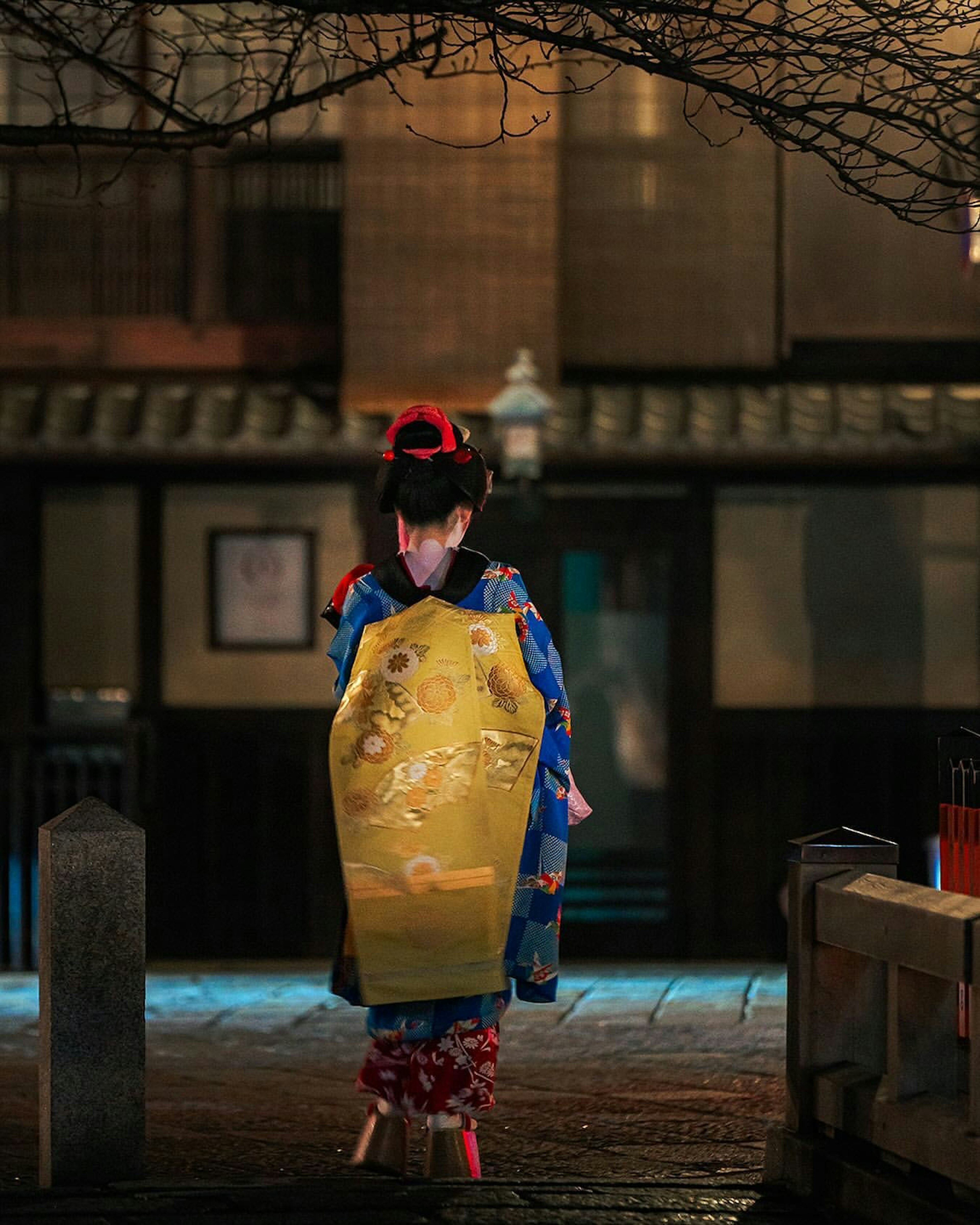 Woman in kimono walking in Kyoto at night with illuminated background